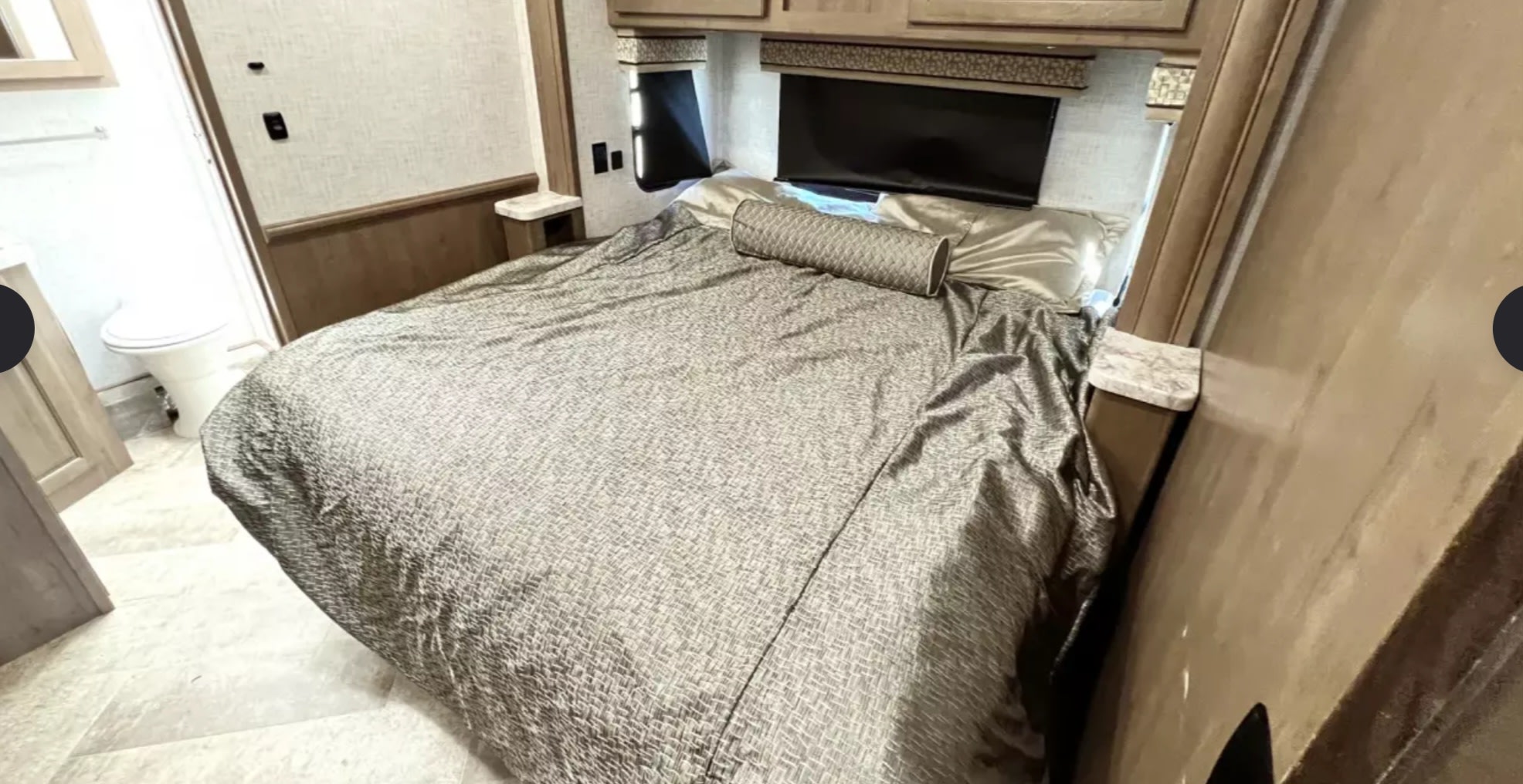 Compact RV rental bedroom interior with a comfortable bed, built-in TV, and adjacent bathroom, ideal for road trips.. Forest River Other 2021