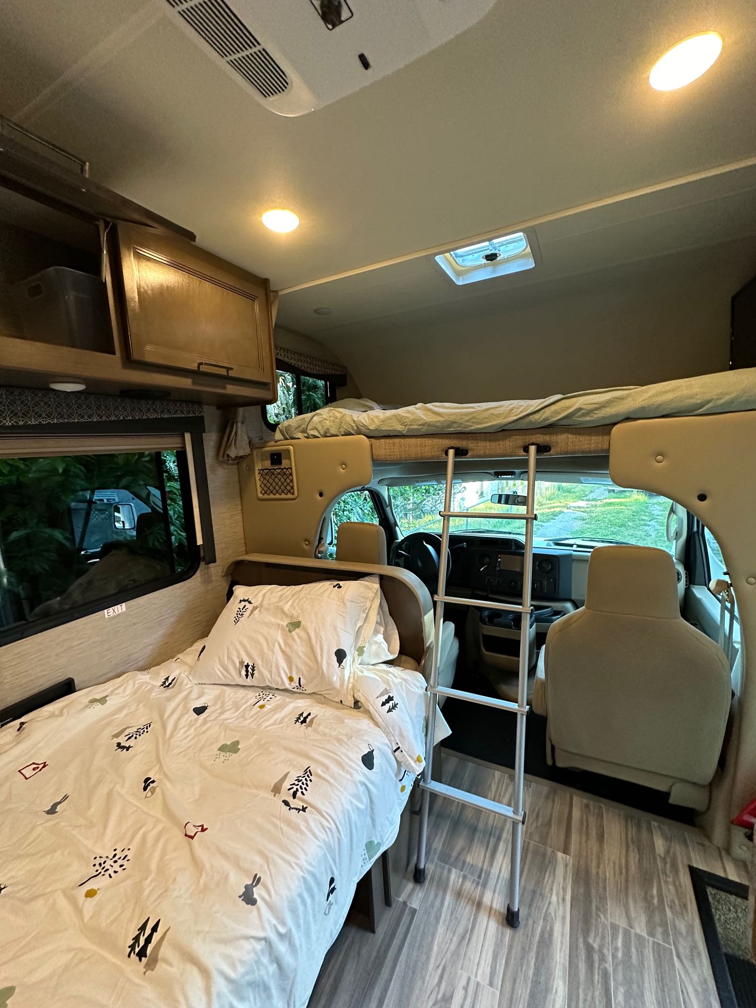 Step inside this RV rental: a cozy interior featuring a lower bed, an overhead bunk with ladder, and the driver's cab.. Thor Four Winds 2021