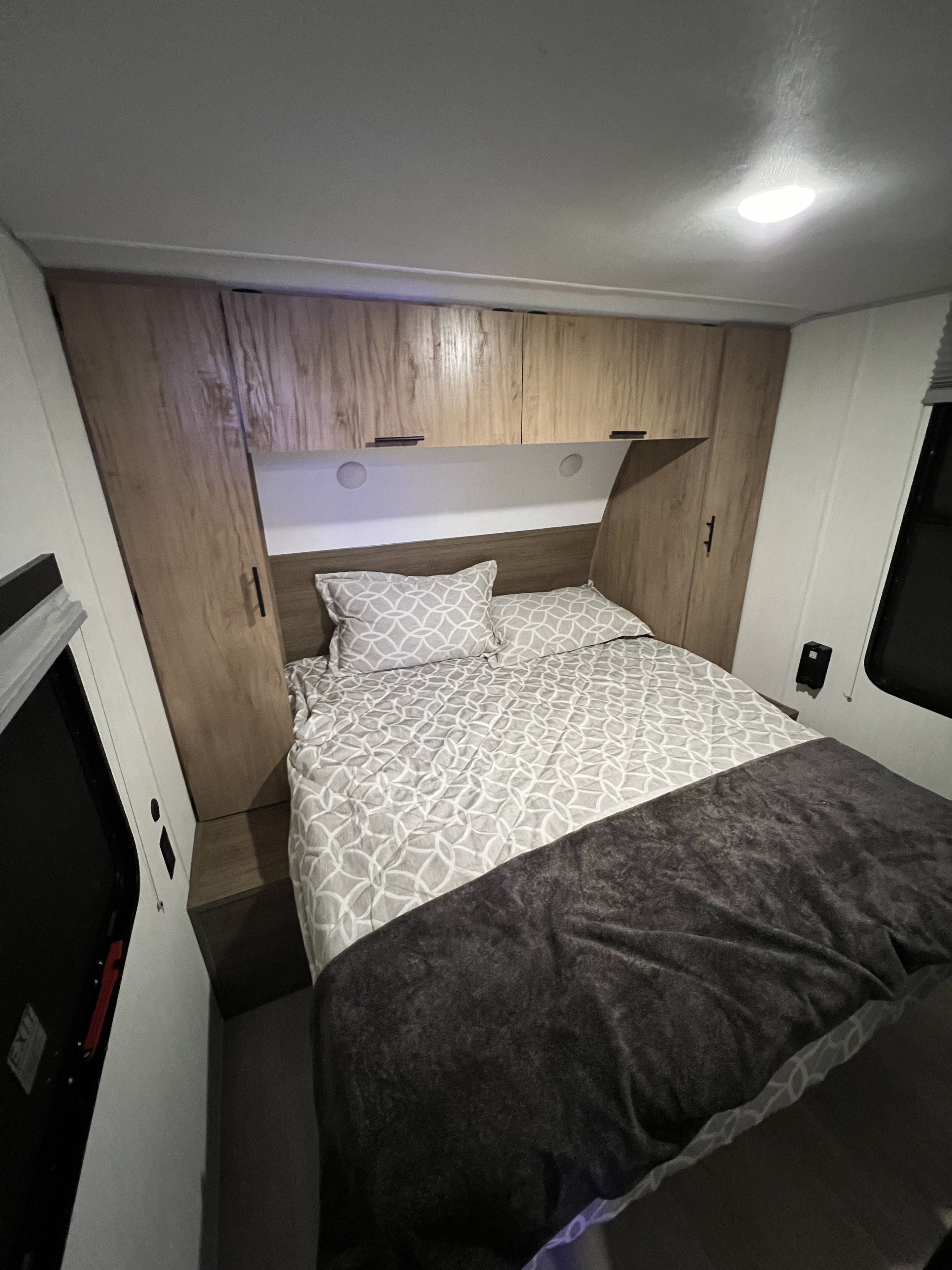 Cozy RV rental bedroom with patterned bedding, built-in cabinets, and bright lighting. Perfect for a comfortable stay.. Cherokee 29TE 2025