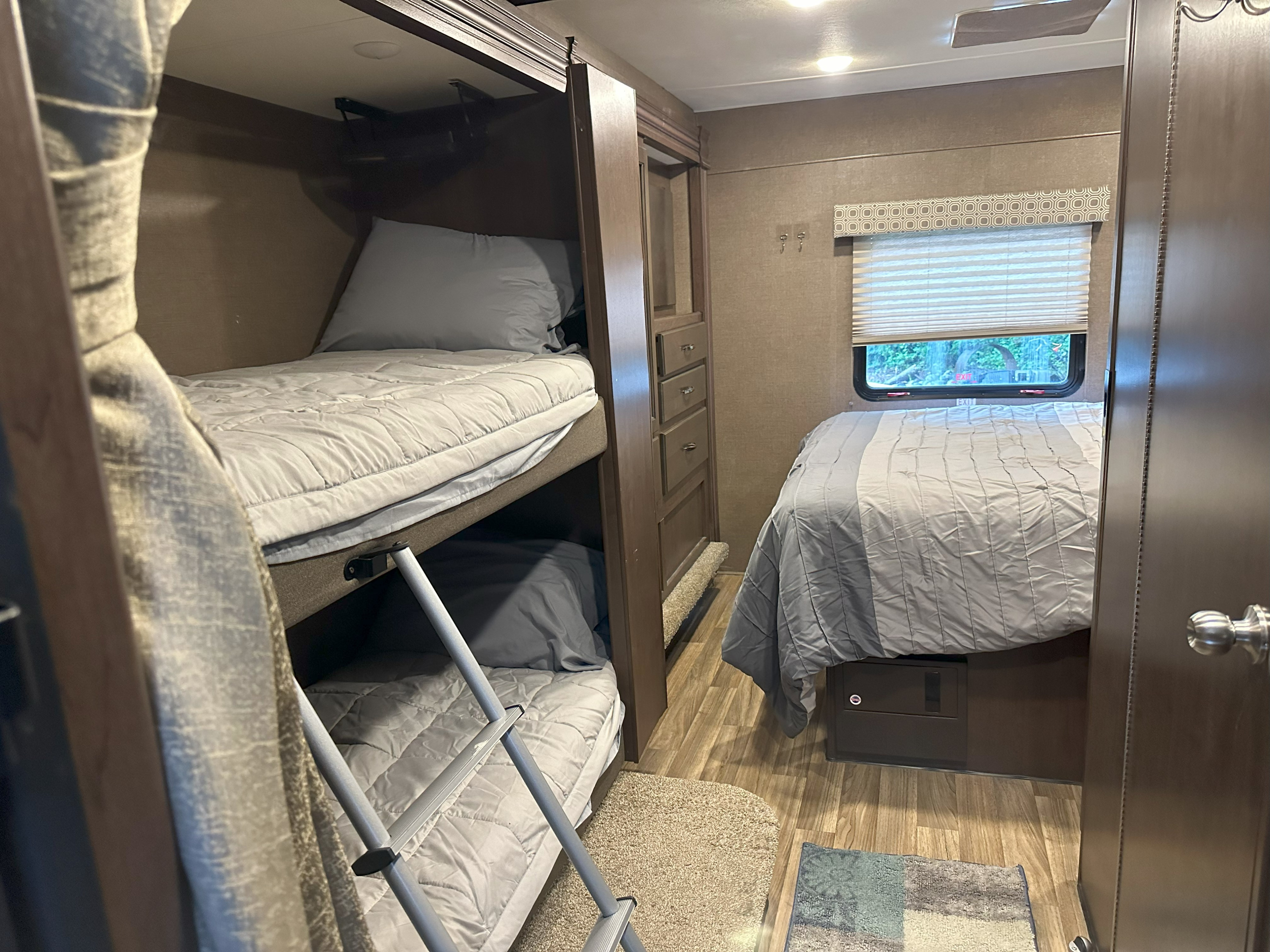 Cozy RV rental bedroom featuring bunk beds, a main bed, and storage cabinetry. Ideal for family adventures.. Thor Four Winds 2019