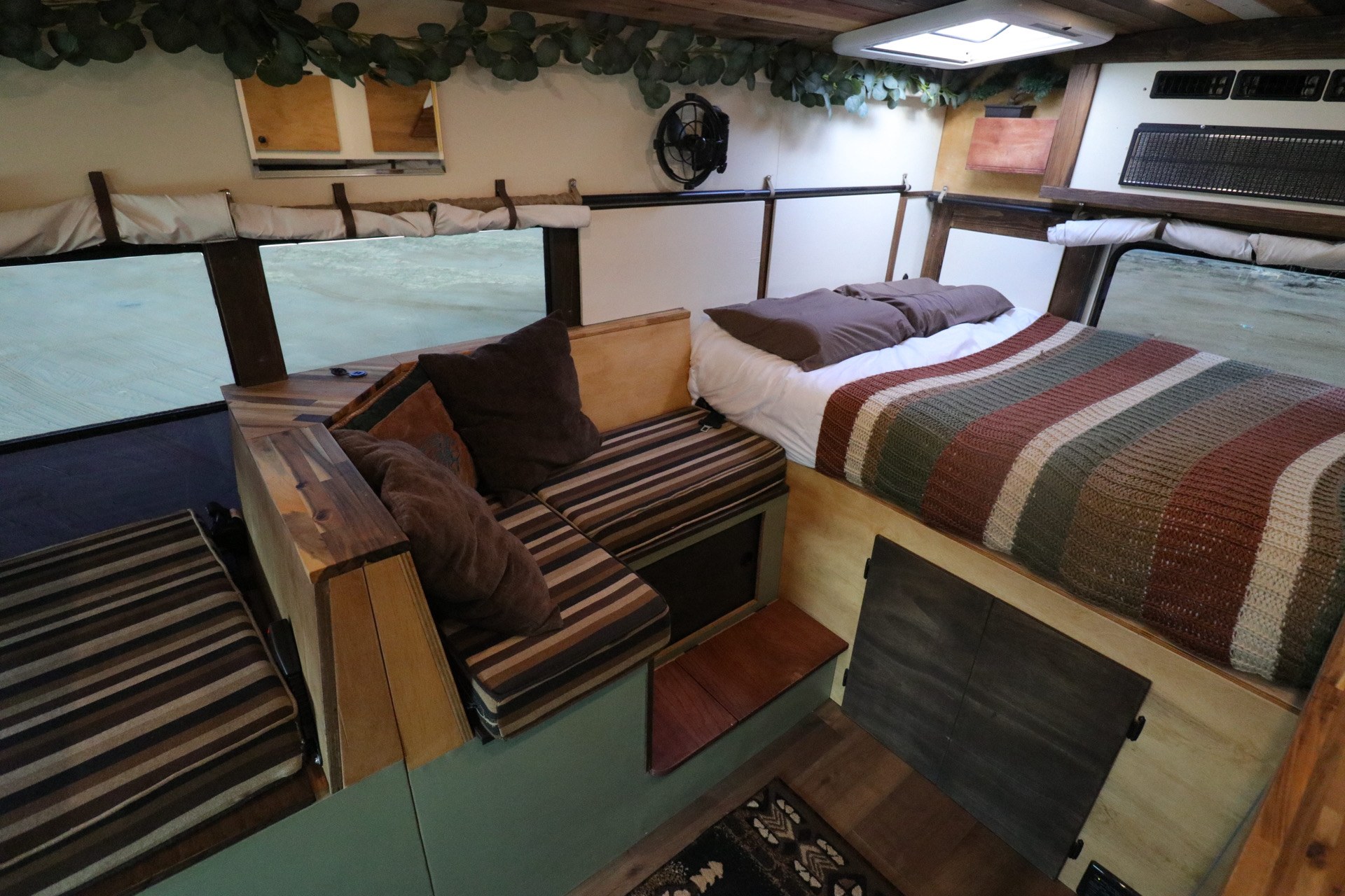 Cozy RV rental interior showcasing a multi-striped bed, lounge seating, and ample windows for scenic views.. Chevrolet Express 2011