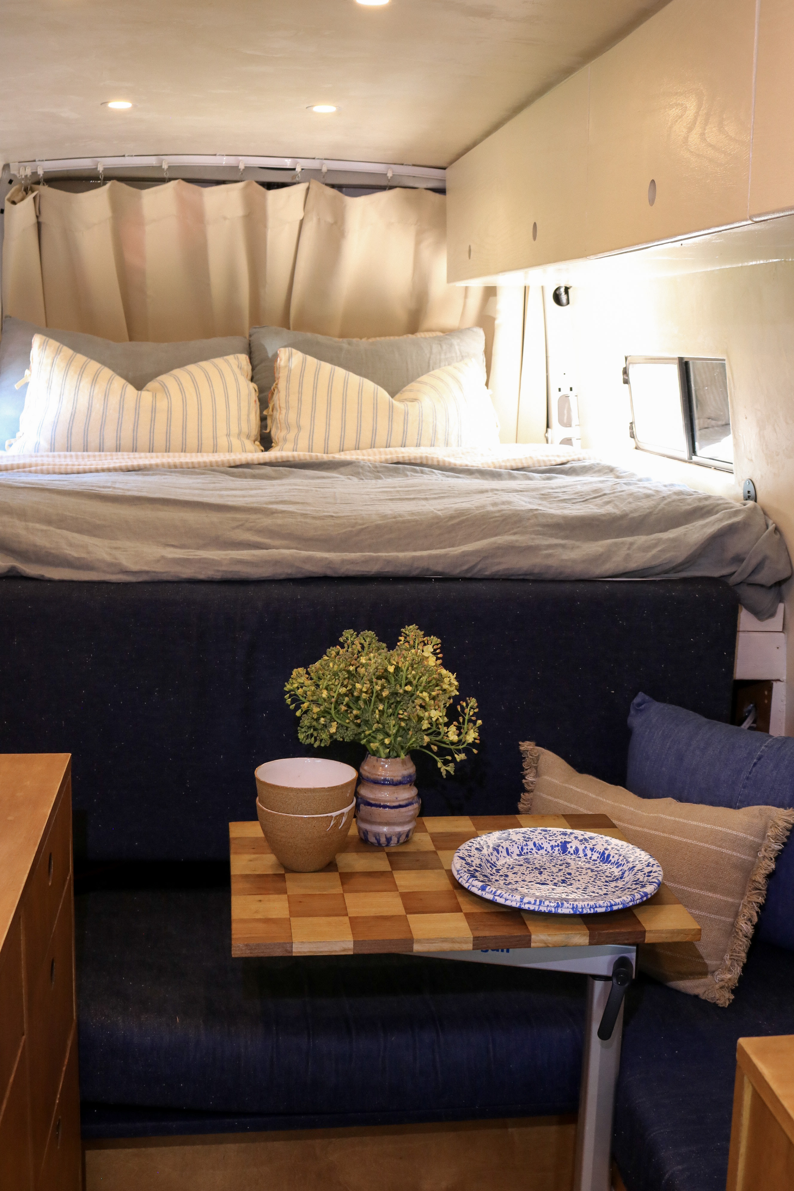 Compact RV rental interior showcasing a comfortable bed, dining table, and cozy bench seating setup.. Mercedes-Benz Sprinter RV Motorhome Campervan 2010