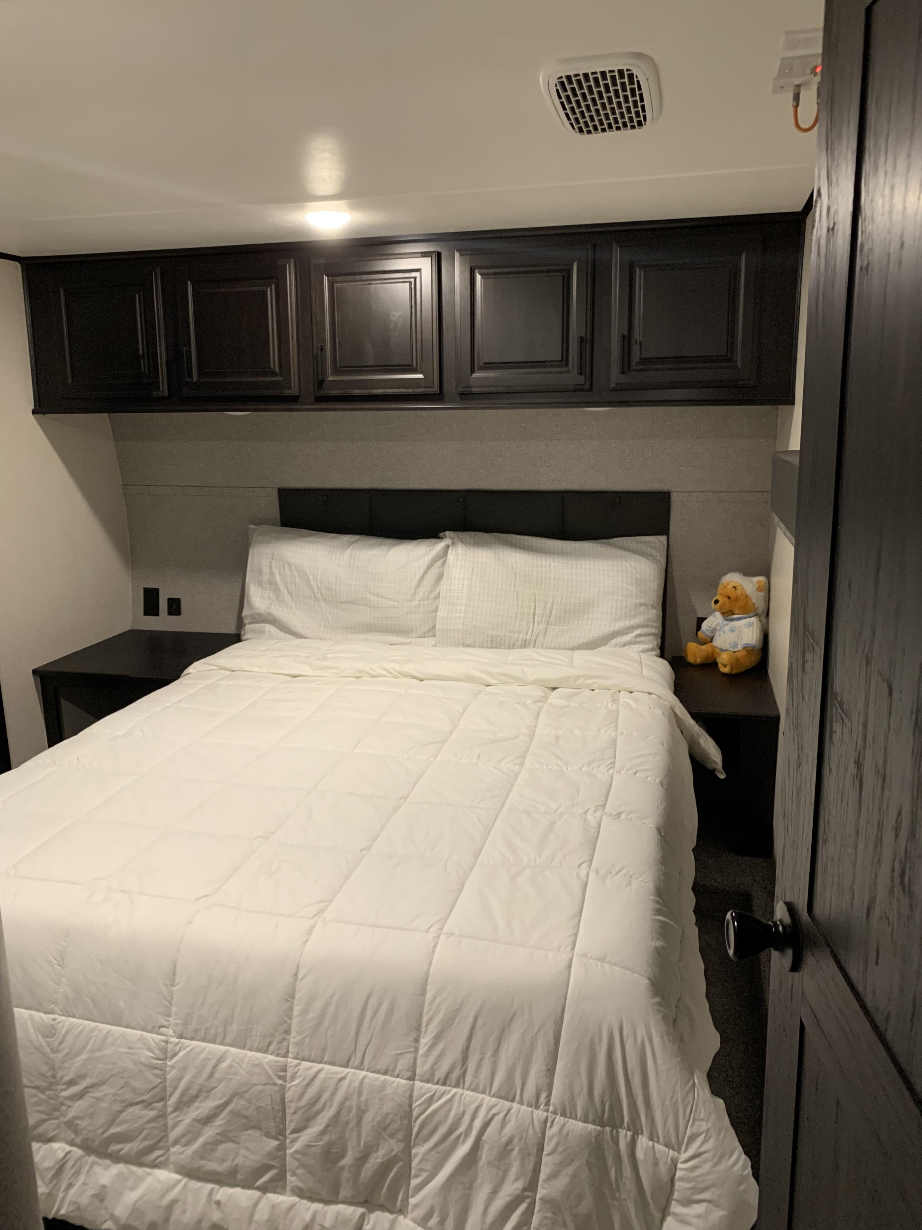 Cozy RV rental bedroom with white bed, overhead cabinets, and nightstands for a comfortable stay.. Highland Ridge RV Mesa Ridge 2021