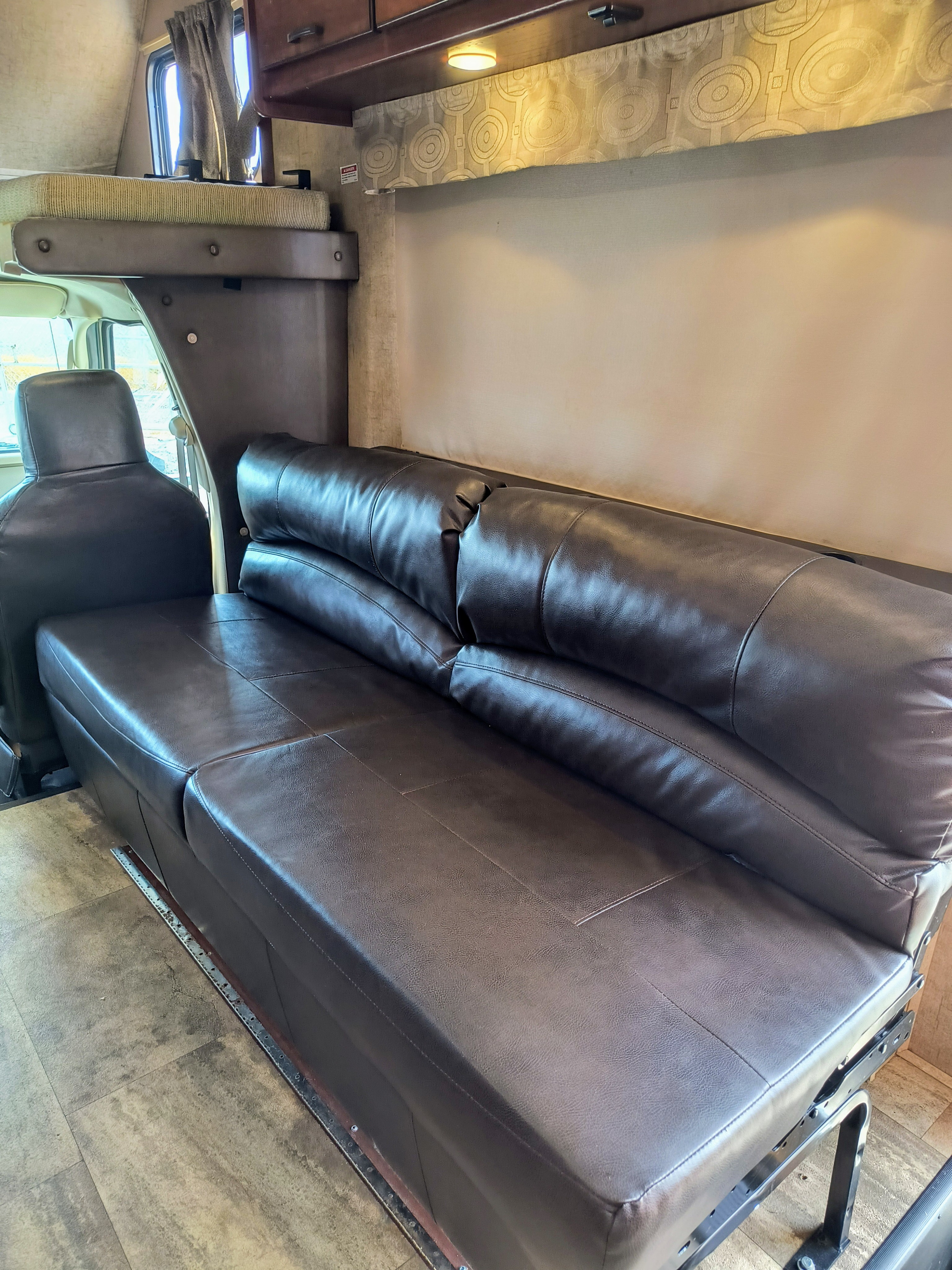 RV rental interior featuring a comfortable dark brown sofa, an overhead bunk bed, and a cozy living area.. Forest River forester 2016