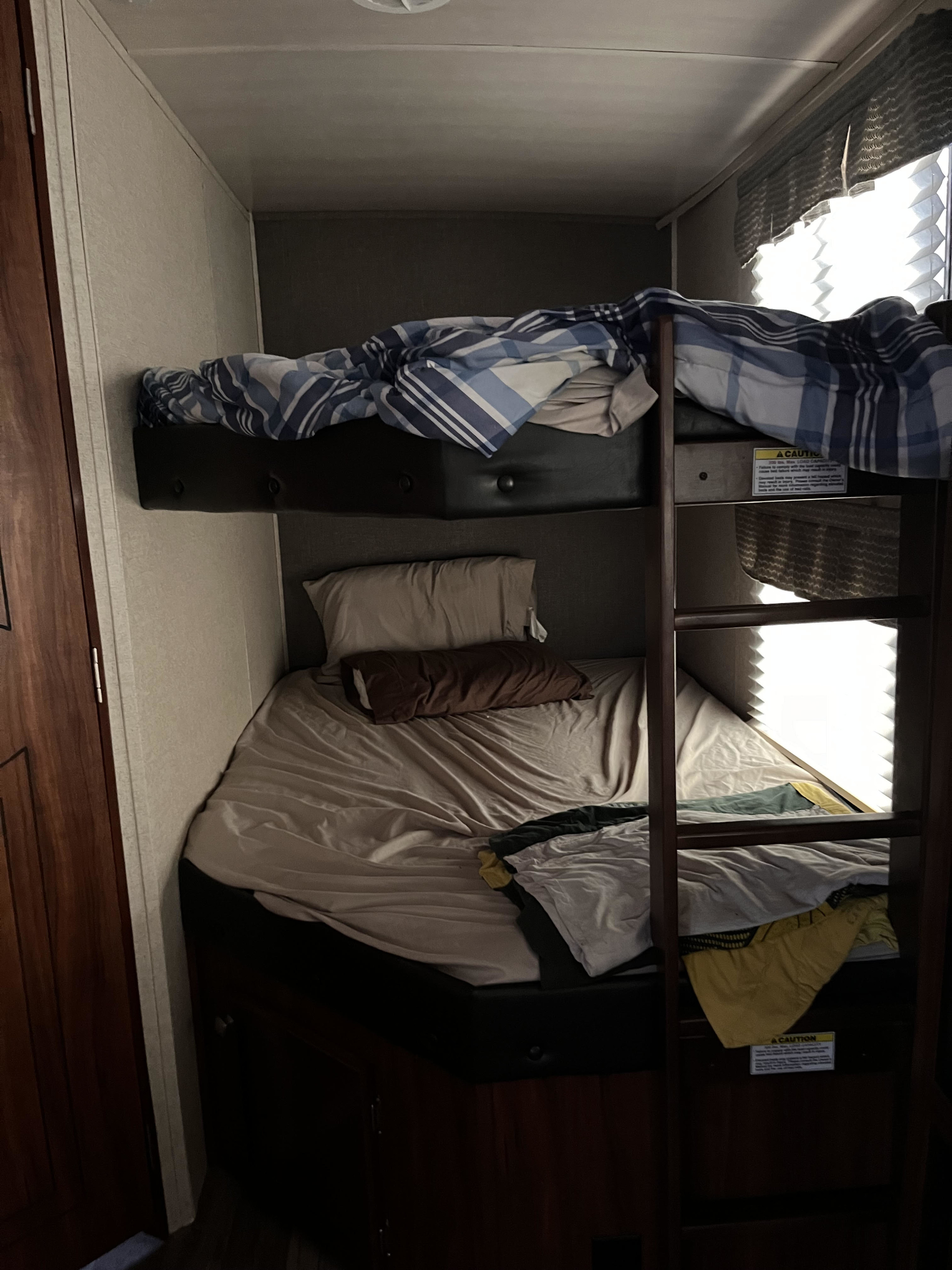 Cozy RV rental bunk beds with a ladder, perfect for compact sleeping in a travel trailer.. Heartland RVs Wilderness 2018