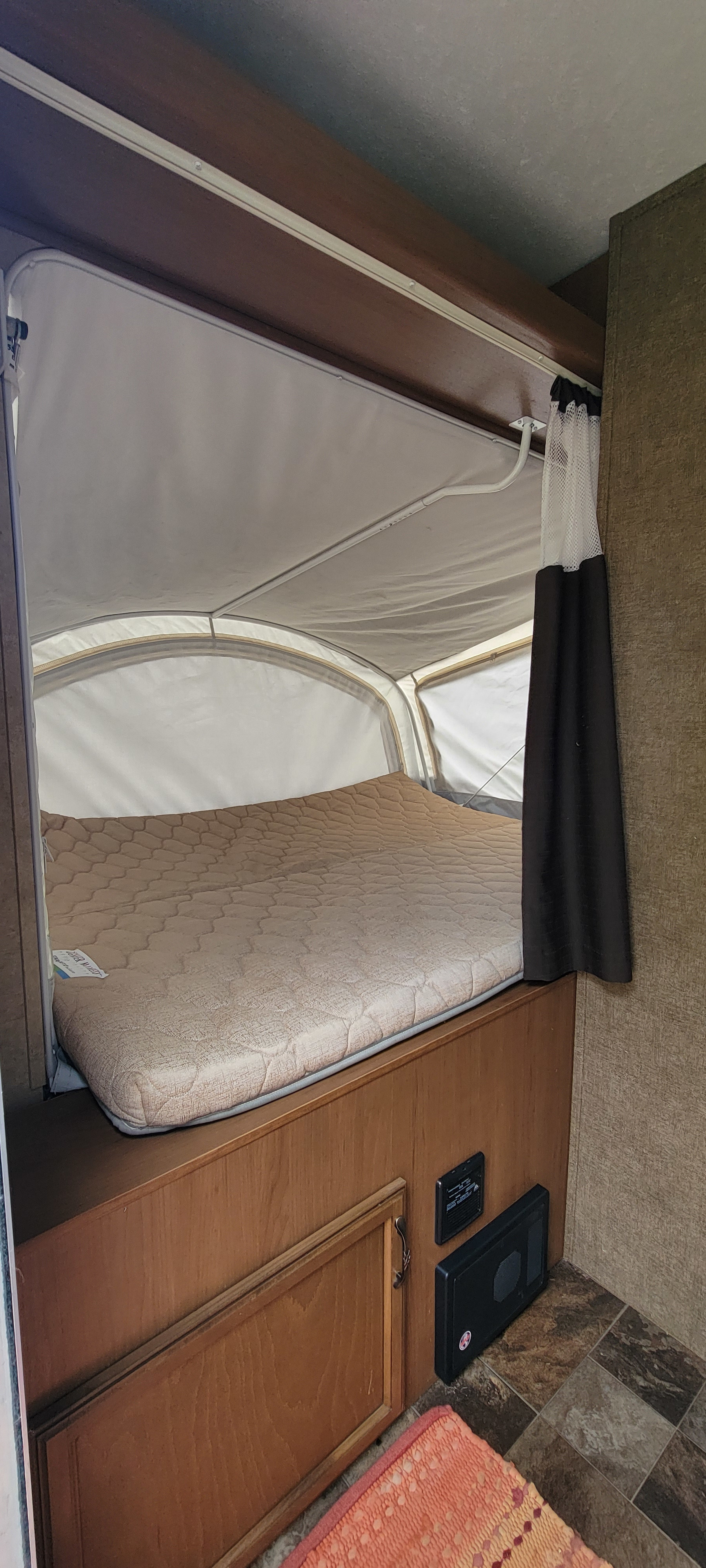 RV rental interior showing a comfortable pop-up bed, storage cabinet, and electrical panel on tiled floor.. Starcraft Travel Star 2014