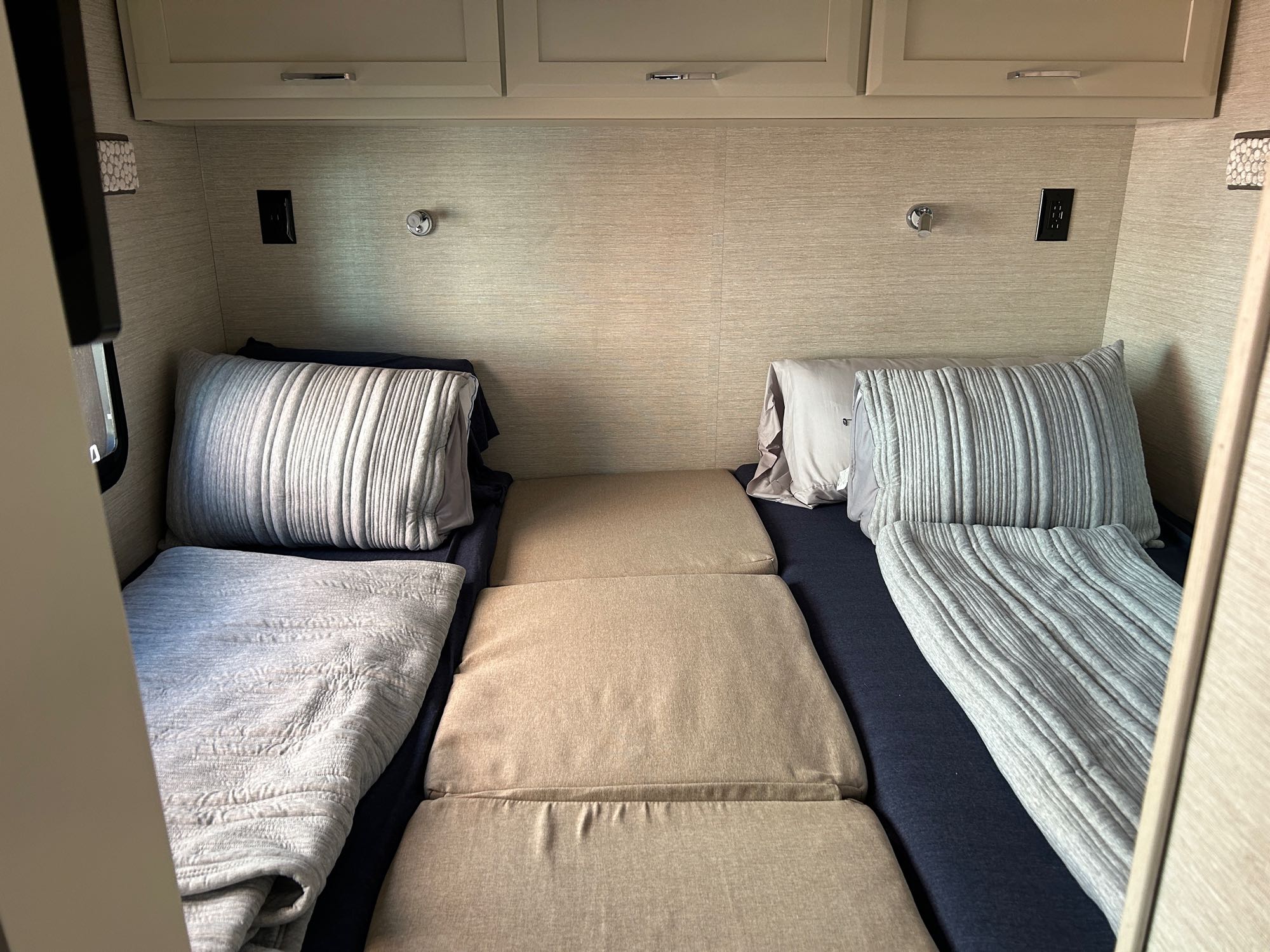 Inside an RV rental: two compact beds with pillows & blankets, plus modular cushions. A functional, cozy sleeping area.. Tiffin Midas 2022