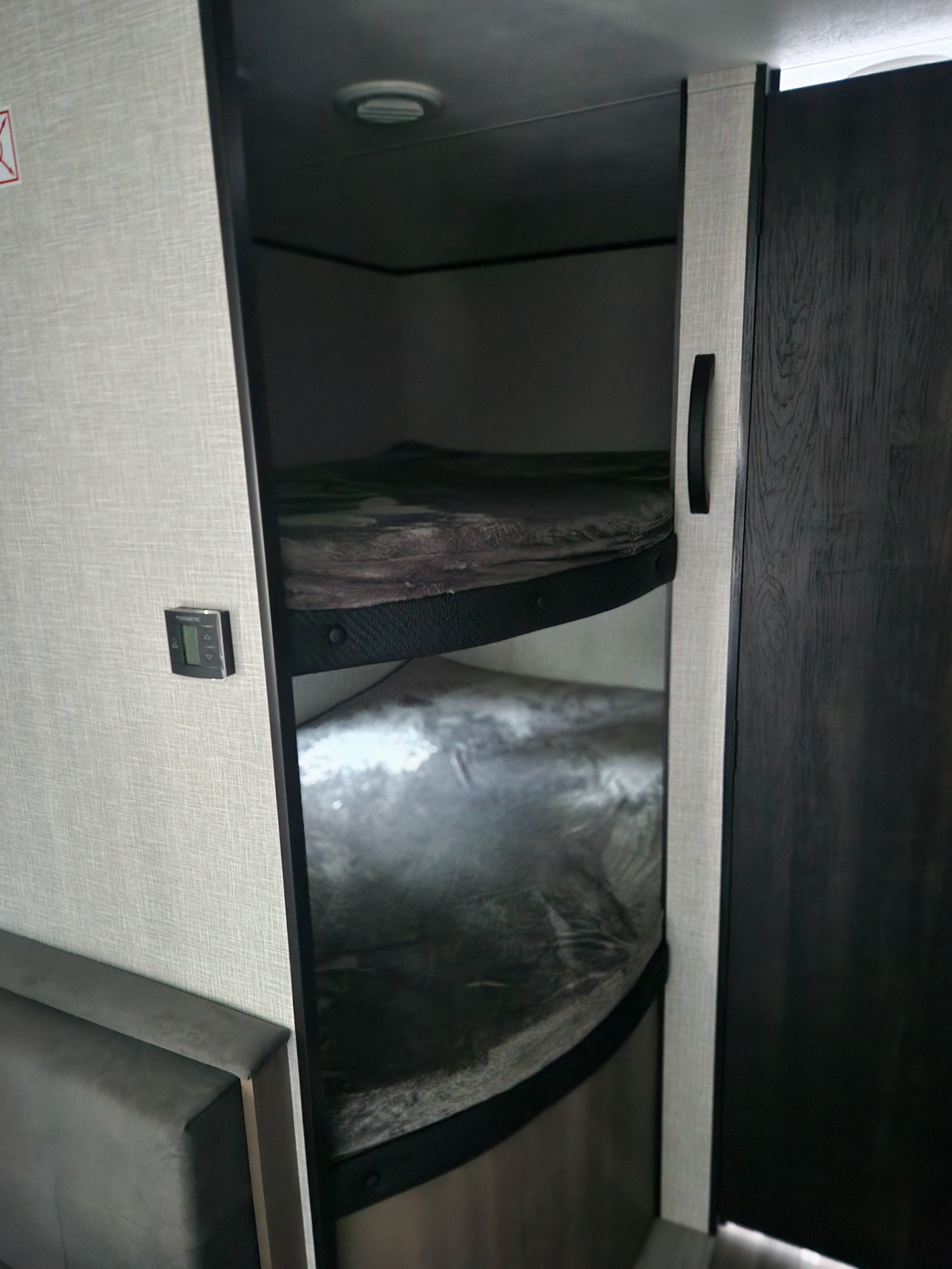 RV rental interior: two bunk beds with protective covers, built-in climate control panel, and seating.. Jayco Jay Flight SLX 2024