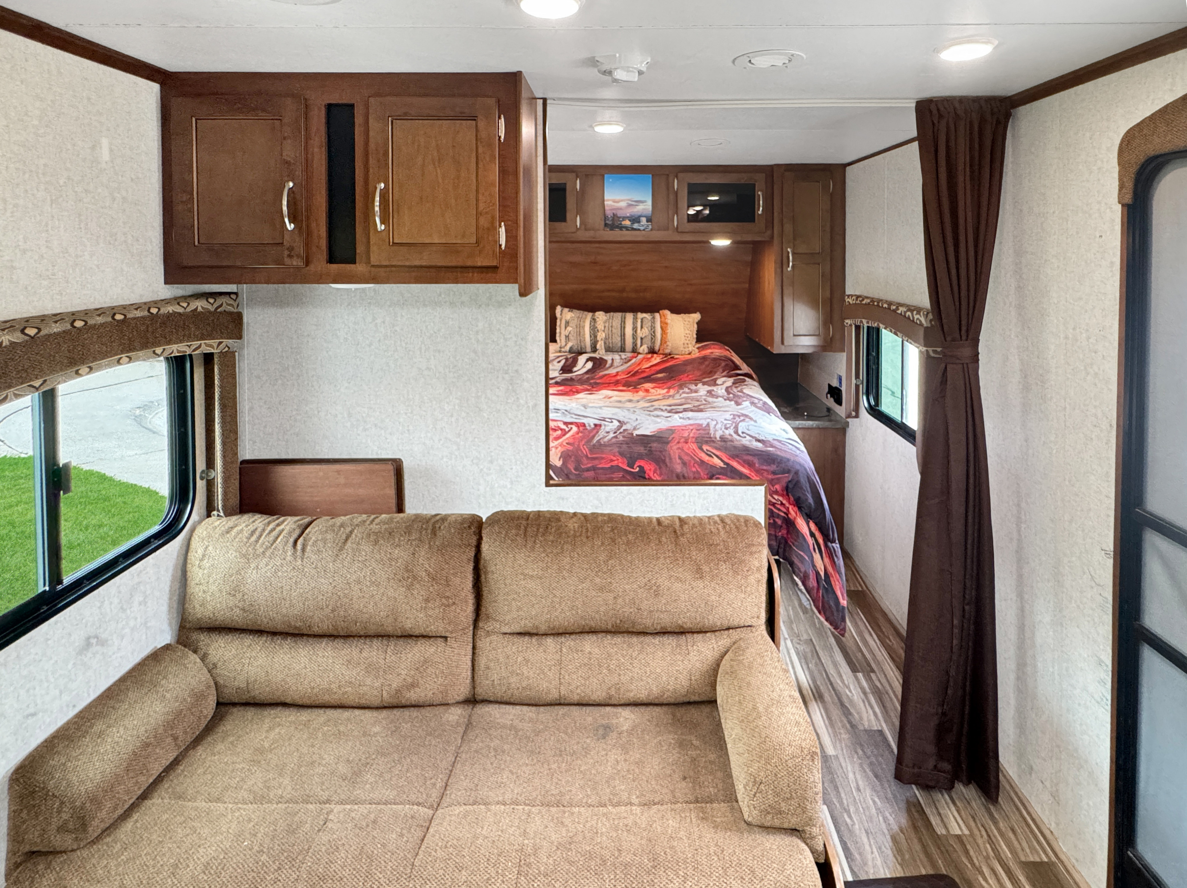 Spacious RV rental interior: view from a comfy sofa looking towards the bedroom with a colorful comforter and cabinets.. Jayco Jay Flight 2014