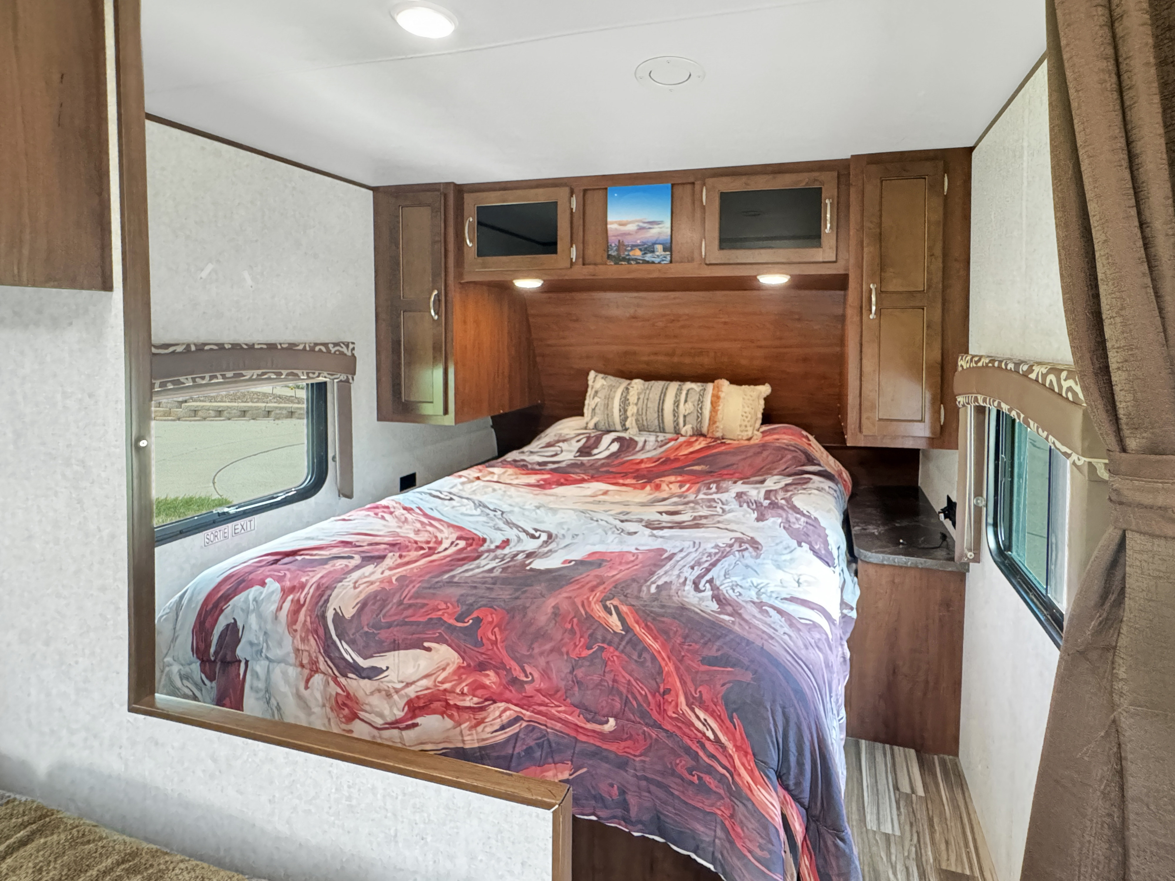 This RV rental features a cozy bedroom with colorful bedding, built-in cabinets, and a window for natural light.. Jayco Jay Flight 2014
