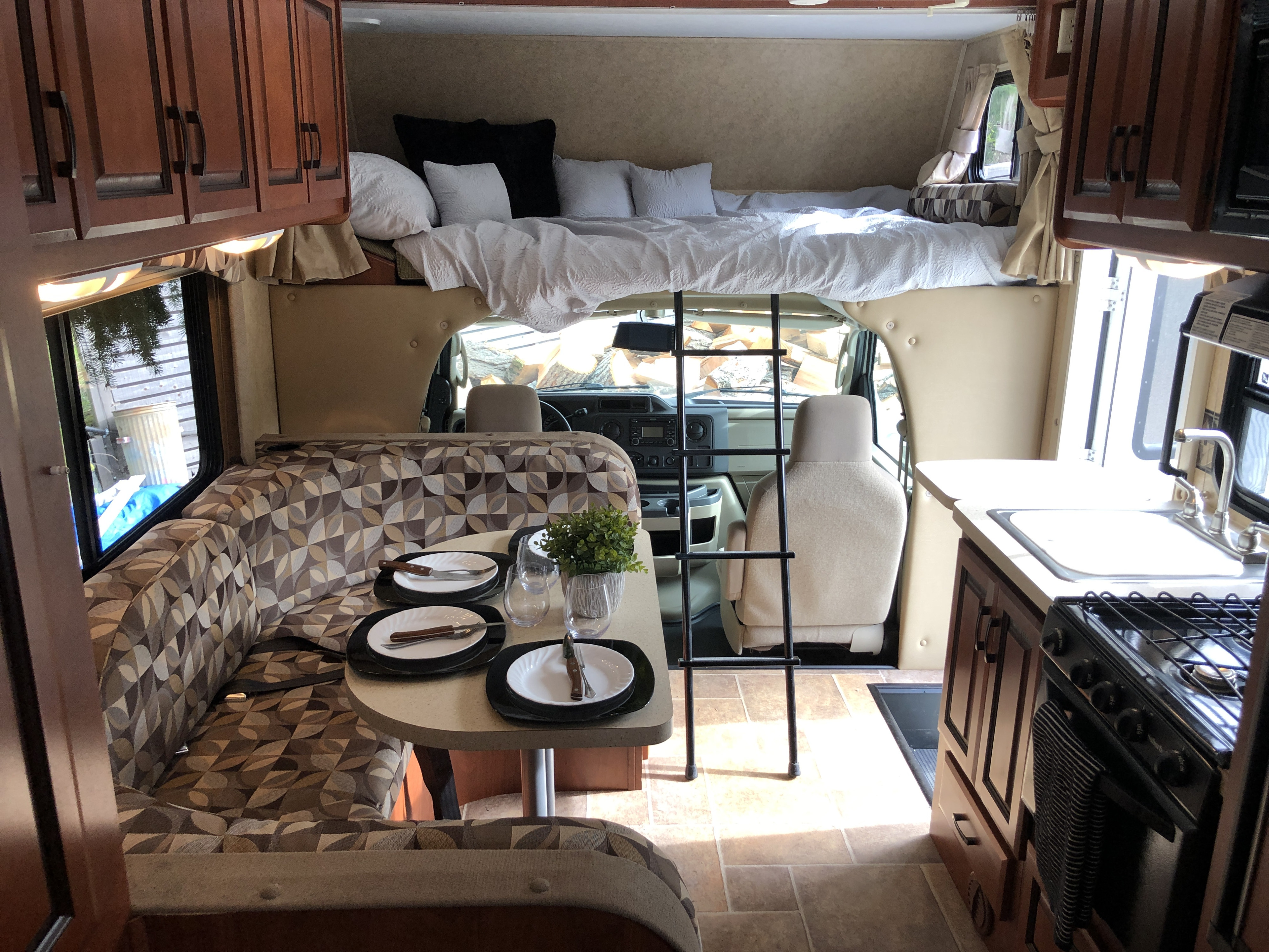 This inviting rv rental interior features a dining booth, kitchen, and comfortable over-cab bunk bed with ladder.. Forest River Sunseeker 2011