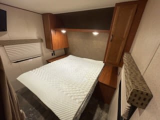 Step inside this inviting RV rental bedroom. Features a comfortable bed with textured topper, abundant storage, and a window.. Jayco Jay Flight 2015
