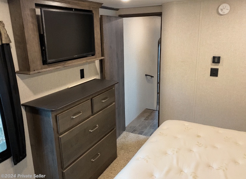 RV rental bedroom showcasing a mounted TV, dresser, and doorway to another area. A comfortable living space.. Keystone RV Montana High Country 2019