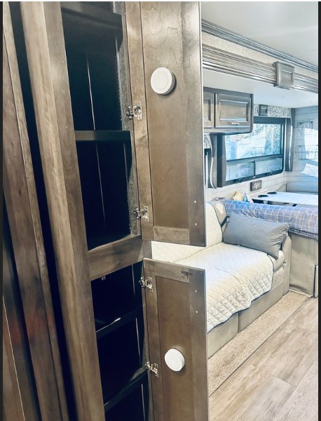 Explore this RV rental's organized interior, featuring open storage cabinets, a comfortable sofa bed, and ample living space.. Fleetwood Bounder 2018