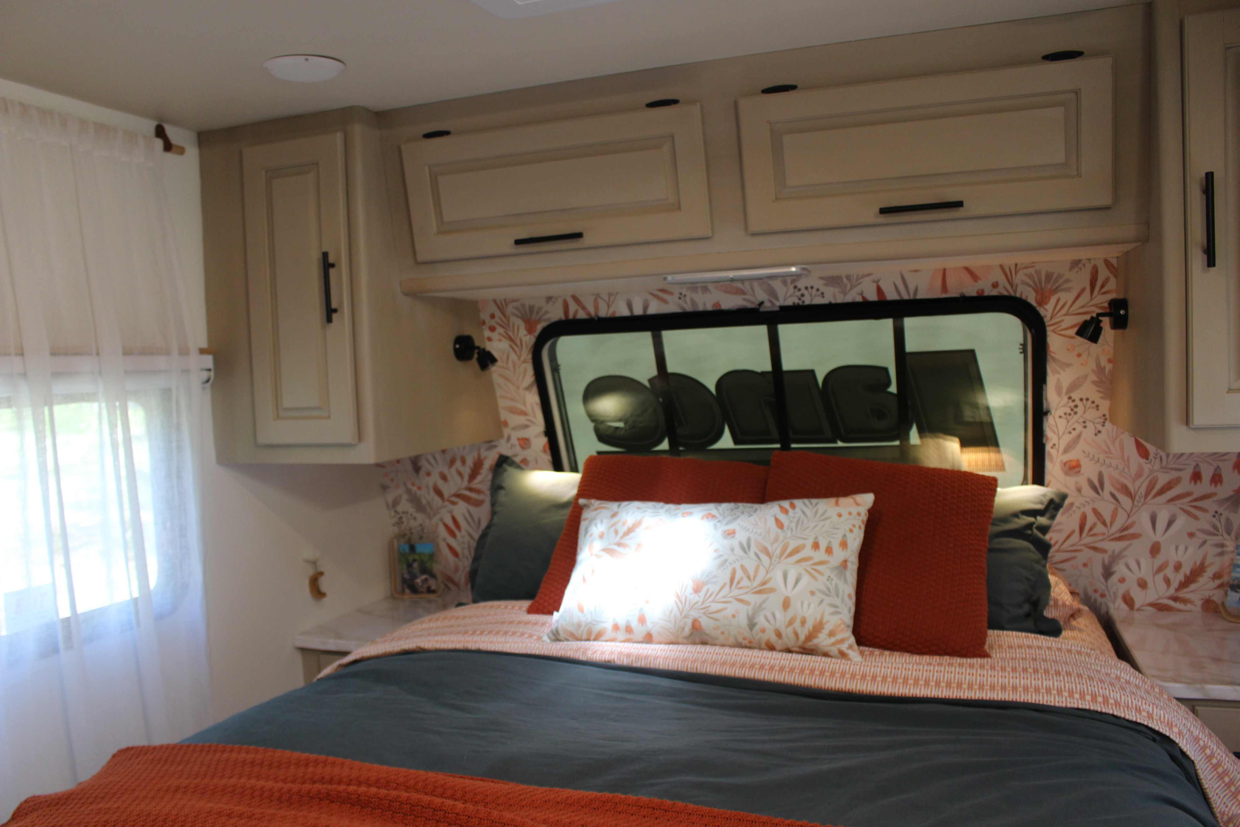 This inviting RV rental bedroom offers a comfortable bed, stylish floral wallpaper, and ample overhead storage.. Lance Manufacturing Lance Manufacturing Trailer 2015