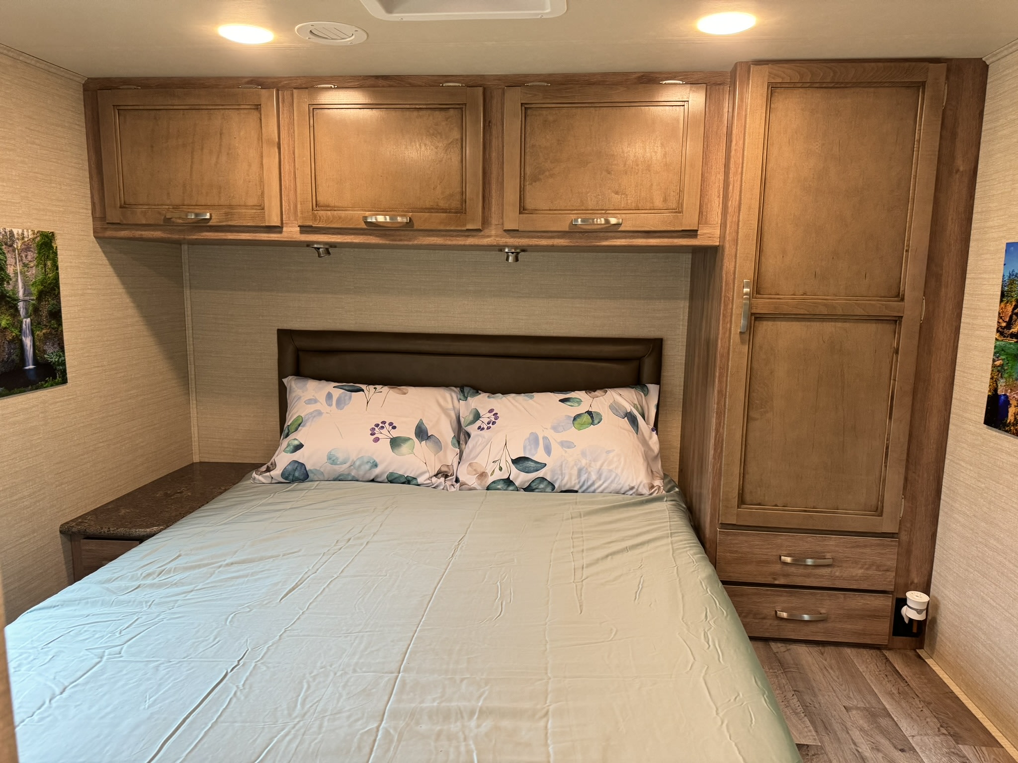 Cozy RV rental bedroom with a bed, patterned pillows, overhead cabinets, and a tall wardrobe, offering ample storage.. Jayco Redhawk SE 2019