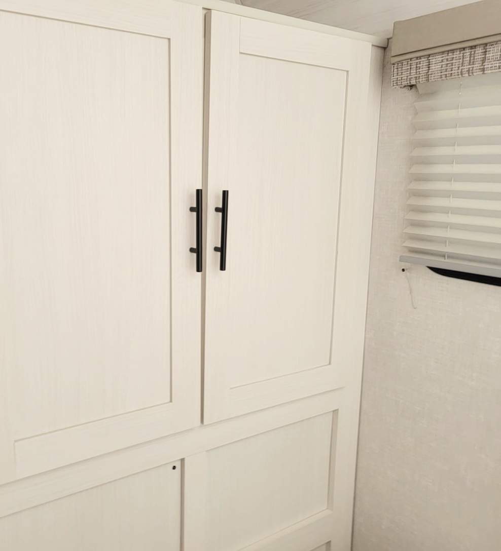 White cabinets & black handles offer storage in this modern RV rental interior. Window with blinds visible.. R-Pod R-Pod Trailer 2022