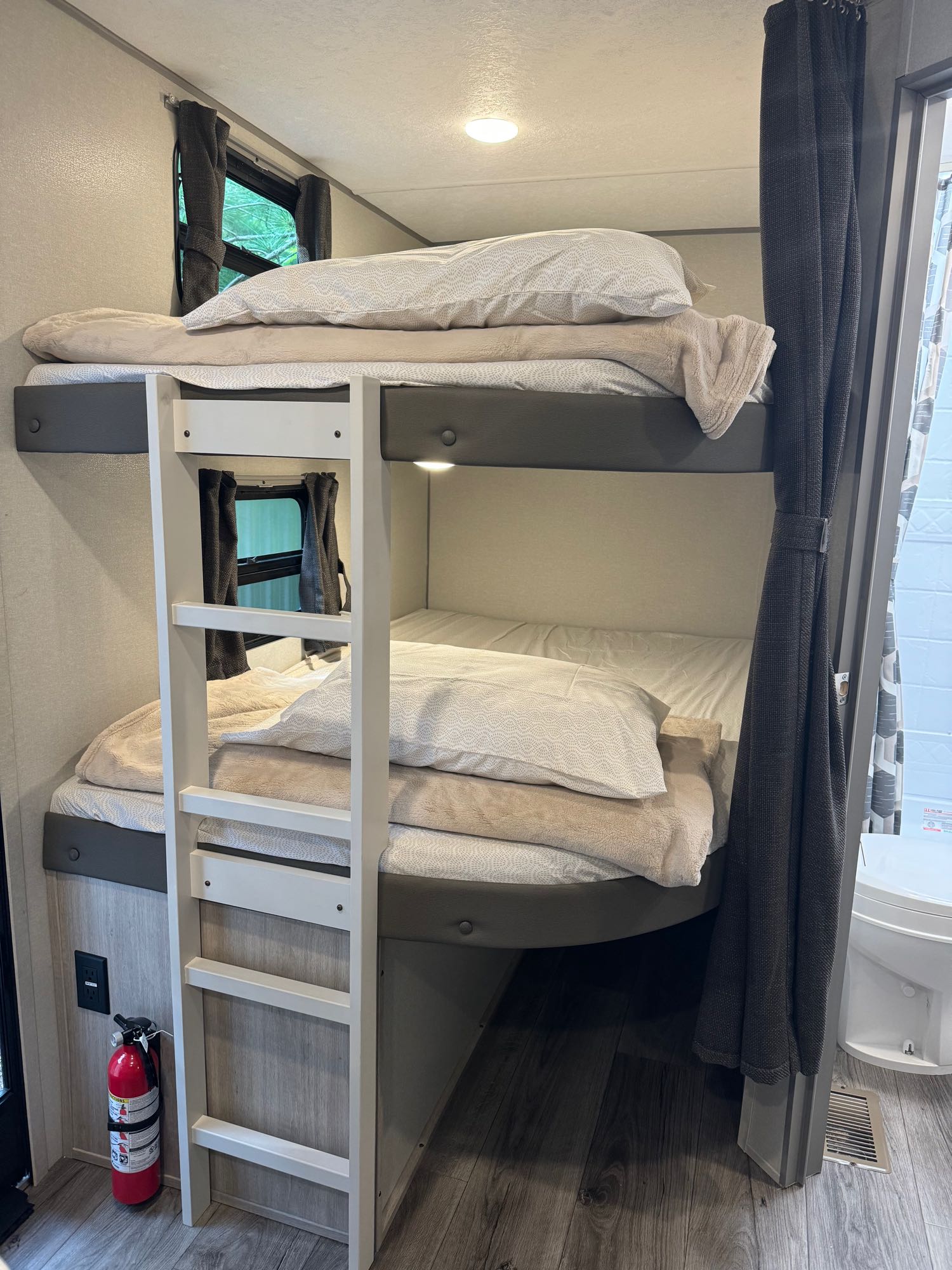 This RV rental features a cozy bunk bed area with two bunks, bedding, a ladder, windows, and a fire extinguisher.. Coachmen Catalina 2024