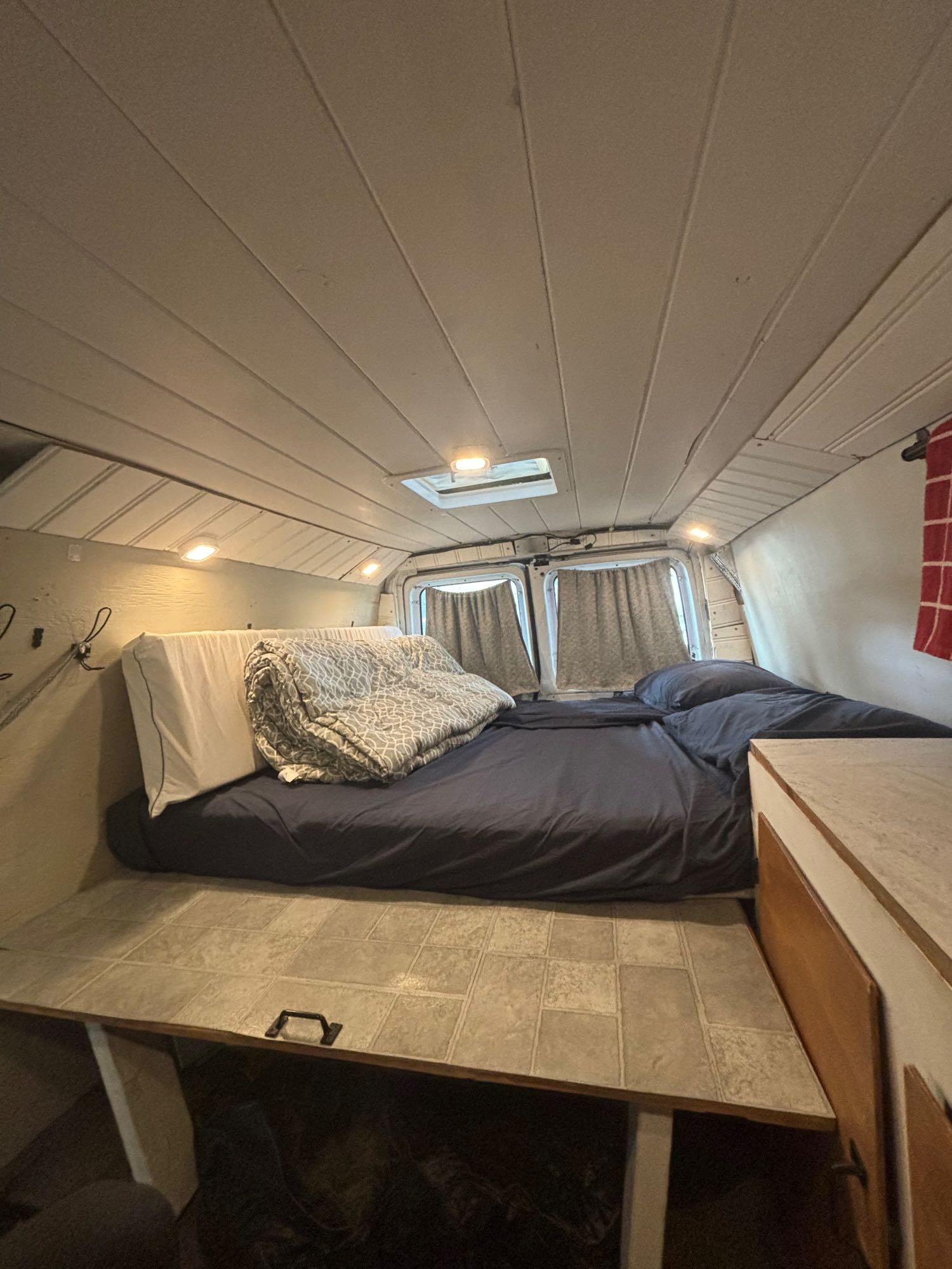Cozy camper van interior. Spacious bed, built-in storage, & overhead lights for an rv rental.. Ford E250 Eagle Camper 2007