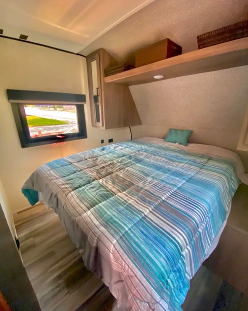 RV rental: Relax in this comfortable bedroom with a striped bed, window, and convenient overhead storage.. Starcraft Autumn Ridge 2022