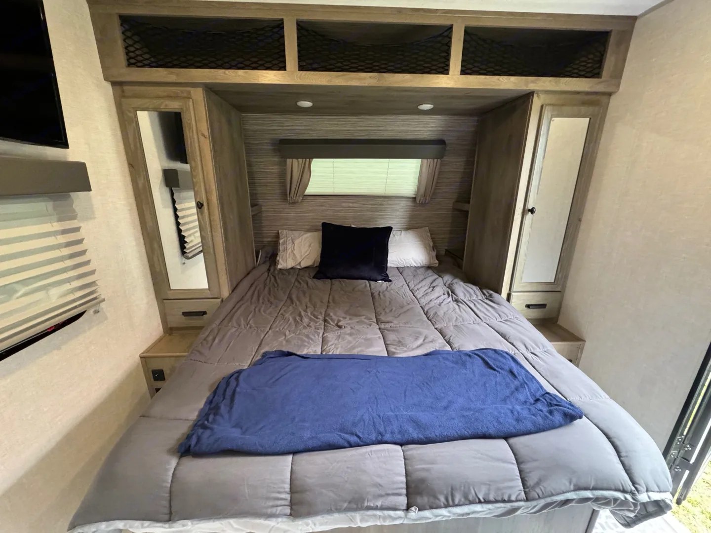 Spacious RV rental bedroom featuring a comfy bed, overhead storage, and mirrored closets. Ideal for travel.. Forest River Surveyor Legend 2022