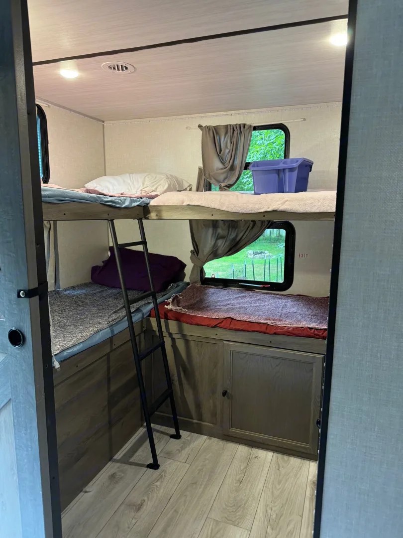 RV rental interior features cozy stacked bunk beds with a ladder, windows, and under-bed storage. A compact sleeping space.. Forest River Surveyor Legend 2022