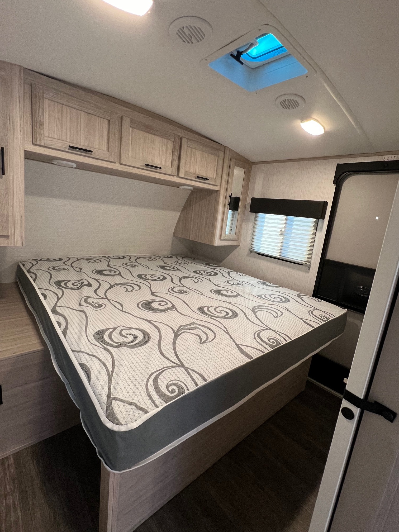 RV rental bedroom showcasing a bed with a distinct patterned mattress, overhead cabinets, and a compact window. Ideal for travel.. Cruiser Rv Corp Shadow Cruiser 2022