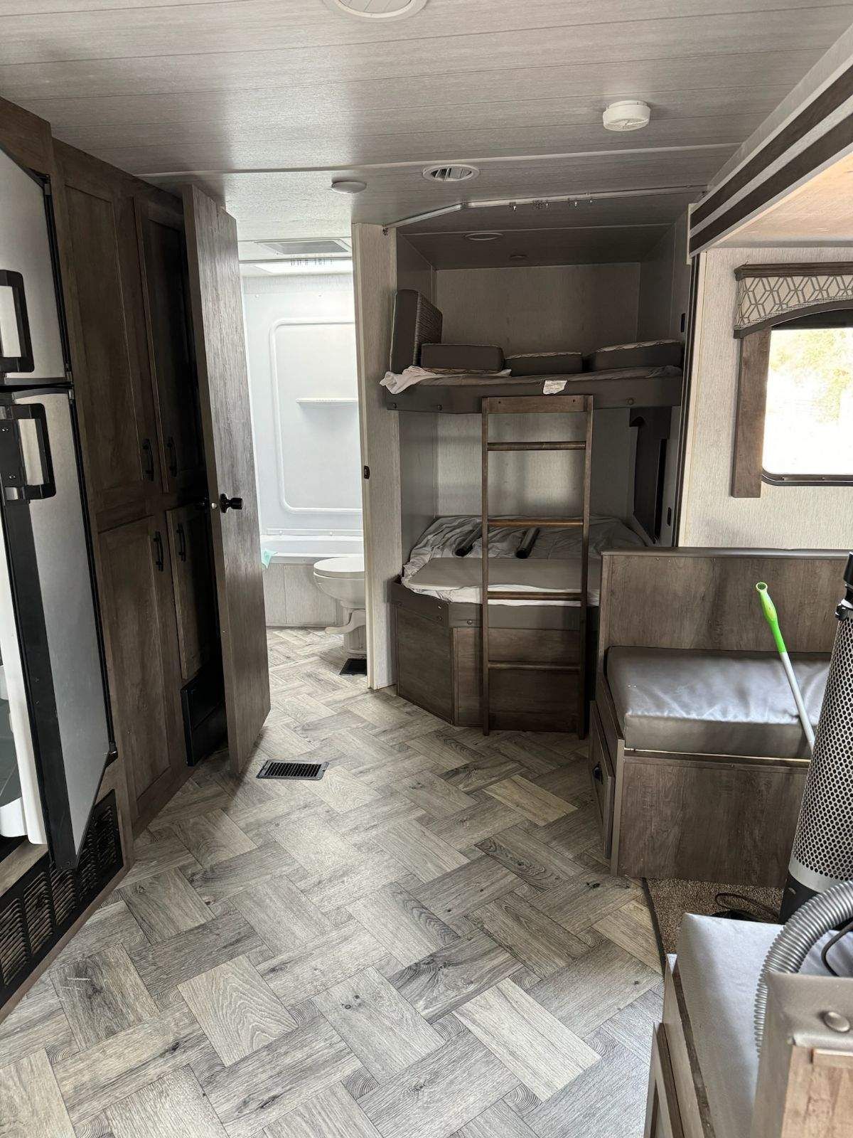 RV rental interior showcasing bunk beds, a compact bathroom, and a dinette area with seating.. Forest River EVO 2022