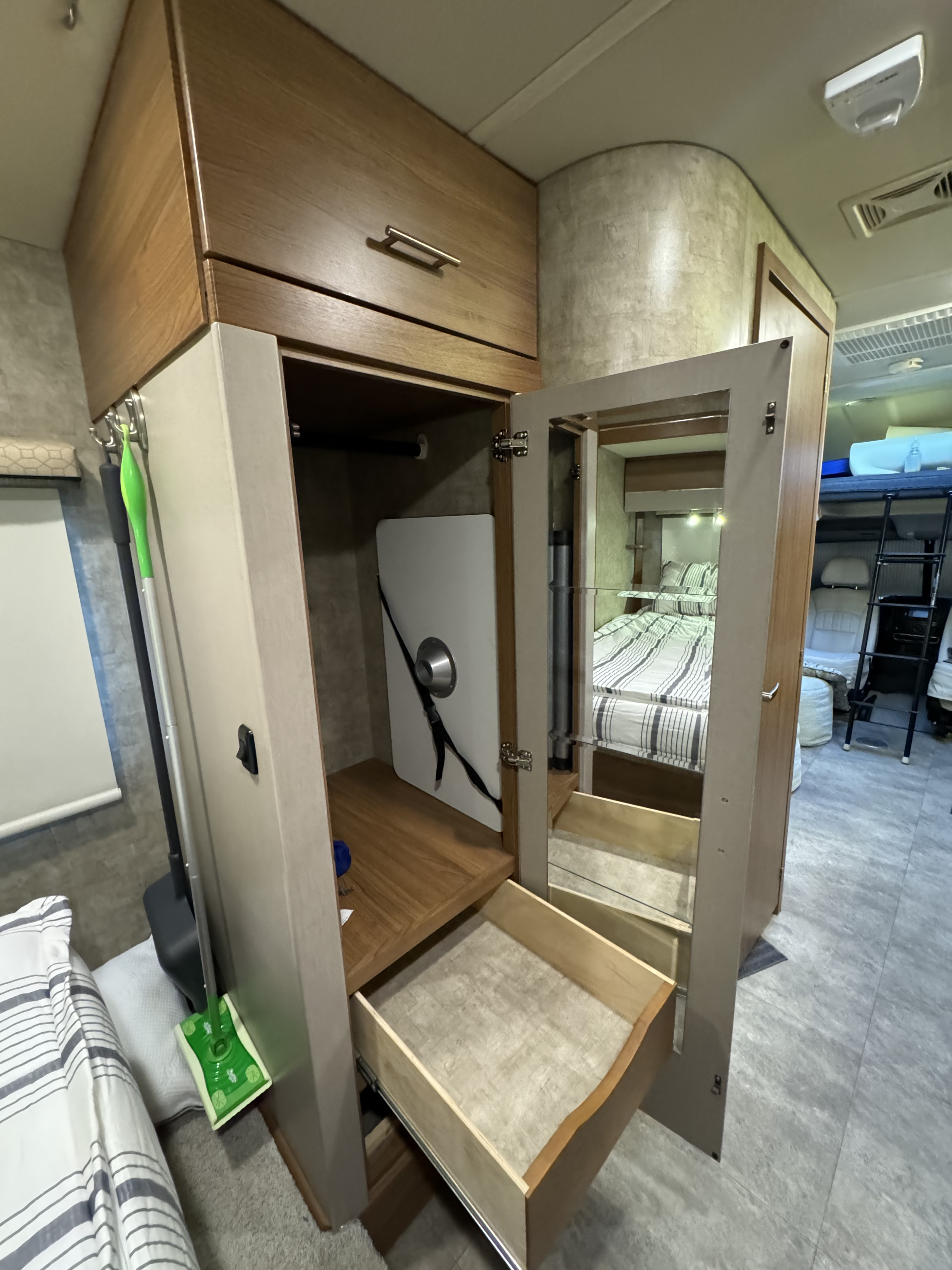 Inside this **rv rental**: an open wardrobe with mirrored door and pull-out drawer, showing ample storage and bed area.. Winnebago View 2015