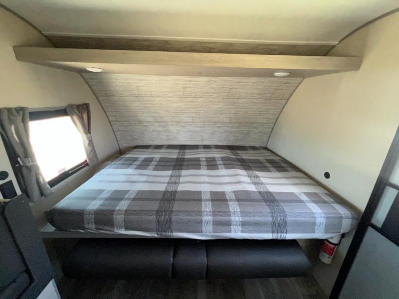 RV rental bedroom: Cozy space with a plaid bed, overhead shelf, and window. Features under-bed seating.. Coachmen Catalina 2022
