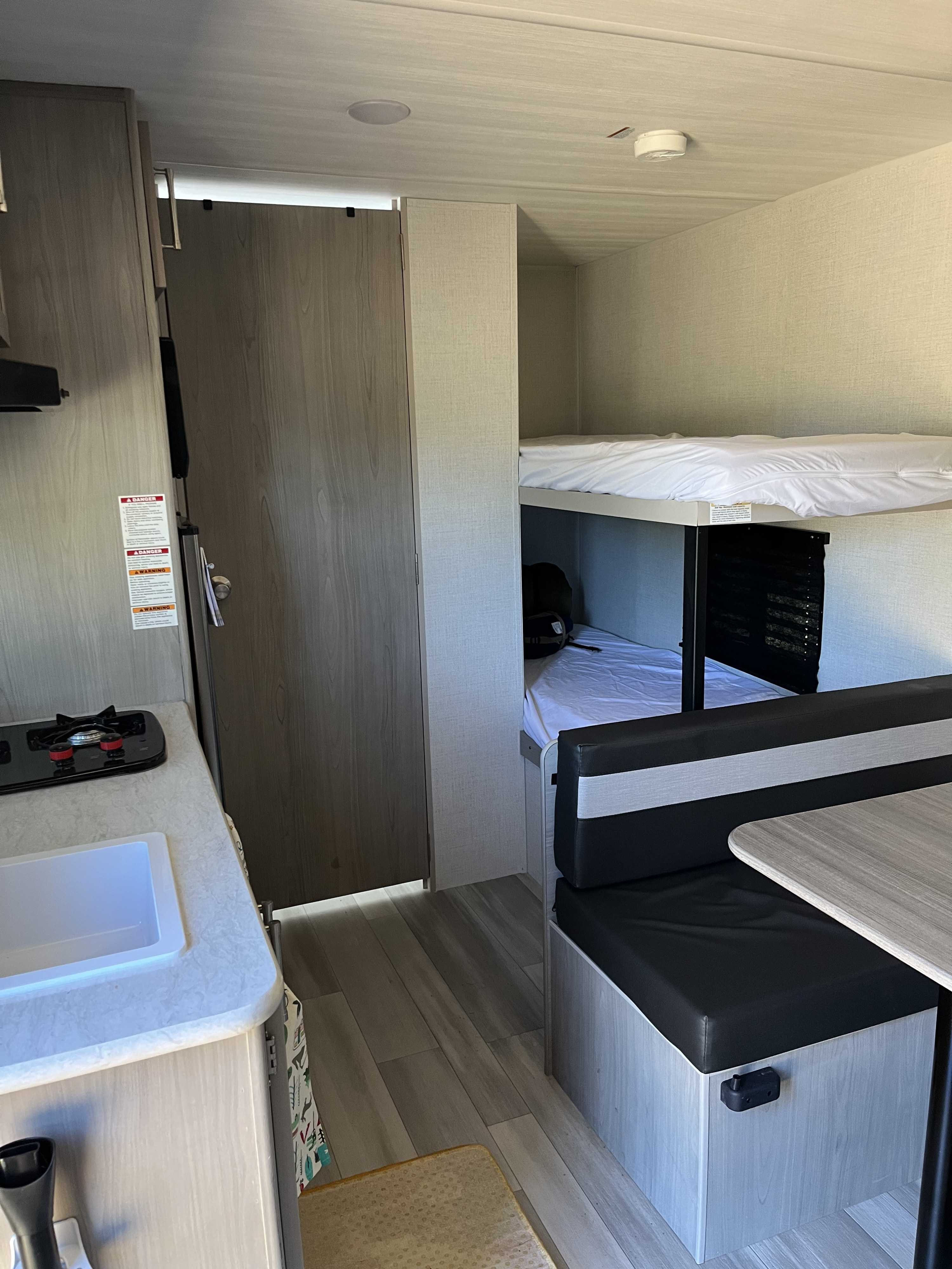 This RV rental interior showcases a compact kitchen, bunk beds, and a dinette, ideal for travel.. Keystone RV Springdale 2024