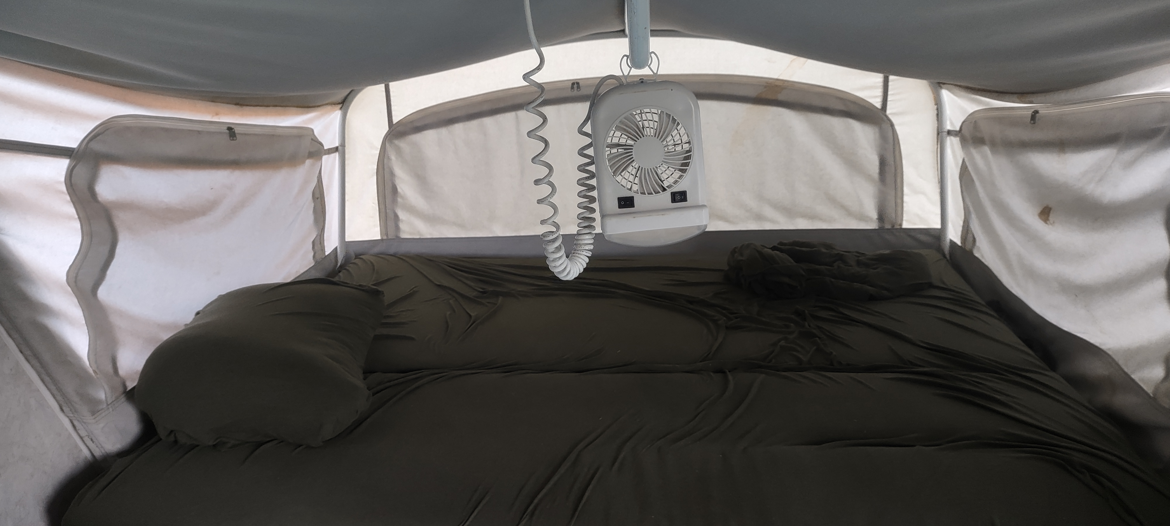 Inside a cozy rv rental, showing a bed with dark bedding and a hanging fan, ready for a comfortable night.. Fleetwood Prowler ultra lite 2000