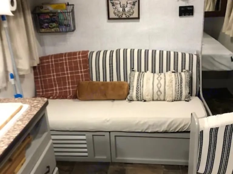 This comfortable RV rental interior features a daybed with patterned pillows and under-seat storage, perfect for travel.. Avenger Avenger 2012