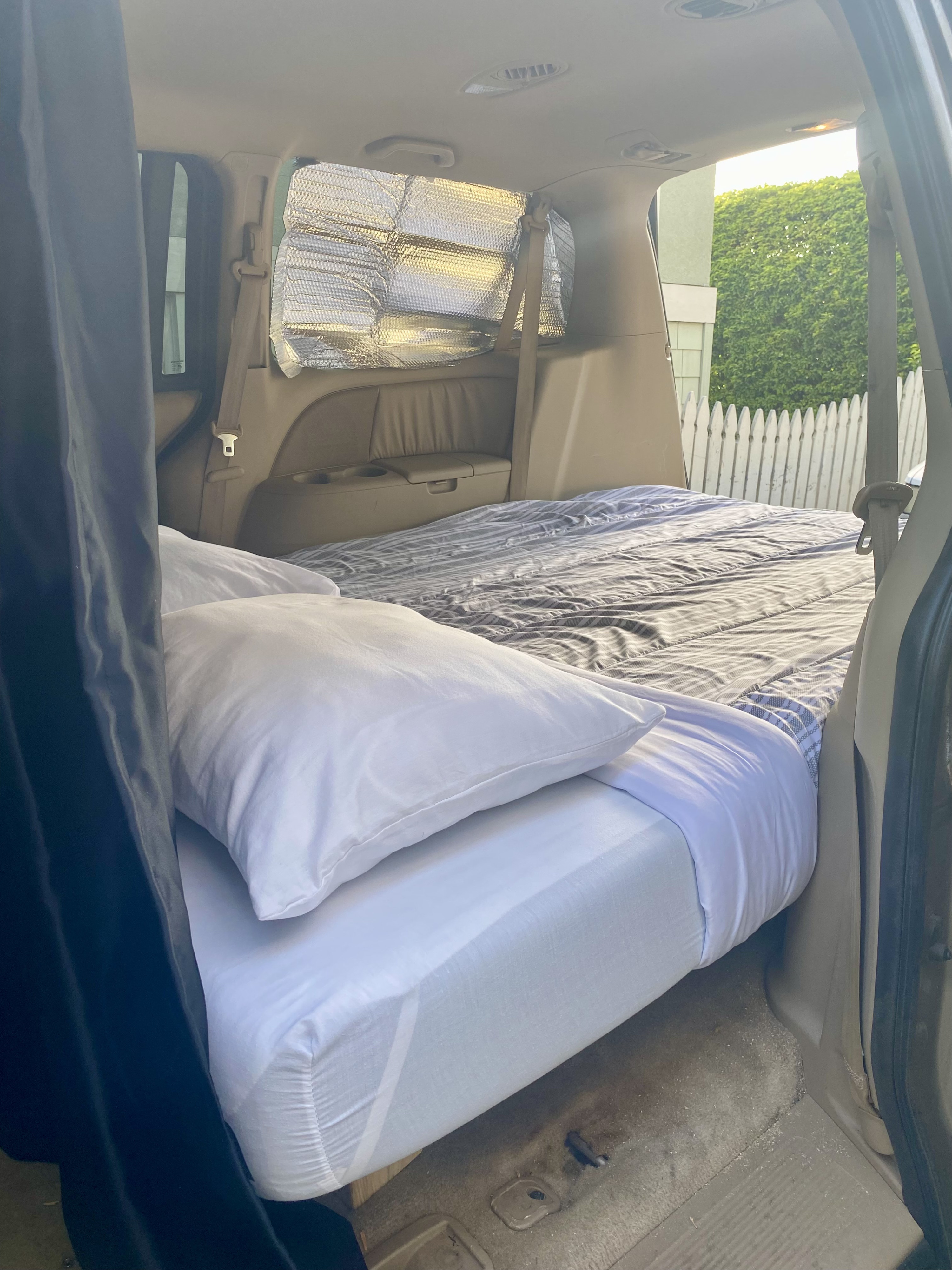 RV rental ready: Vehicle interior converted into a cozy sleeping area with bed, pillows, and reflective window shades.. Odyssey Honda 2007