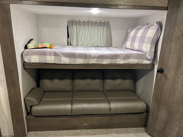 This RV rental features a cozy bunk area: top bunk with quilt, and a convertible sofa bed below. Compact, efficient space.. Forest River Salem 2020