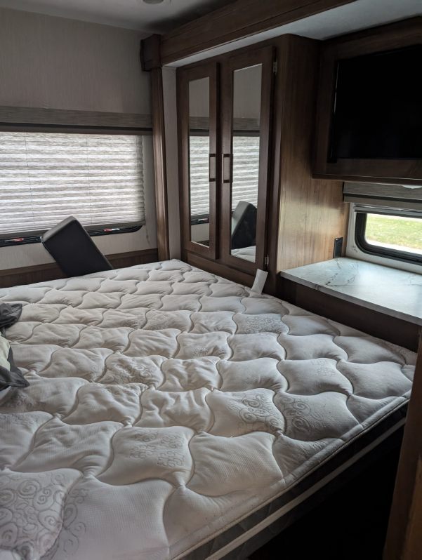 This RV rental offers a comfortable bedroom with a large mattress, mirrored wardrobe, and mounted TV.. Coachmen Pursuit 2021