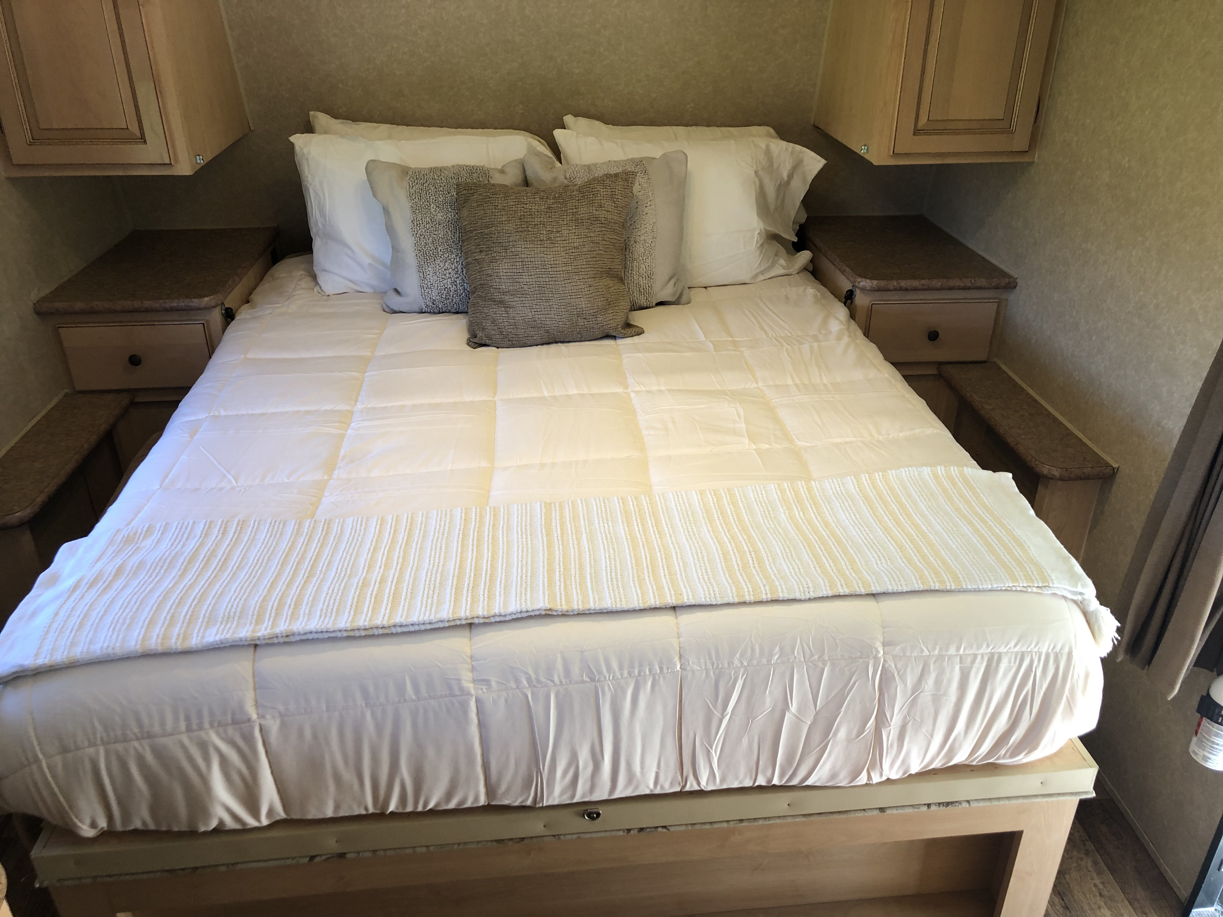 RV rental interior: cozy bedroom with cream bedding, accent pillows, side tables, and overhead cabinets.. Forest River Rockwood Mini Lite 2012