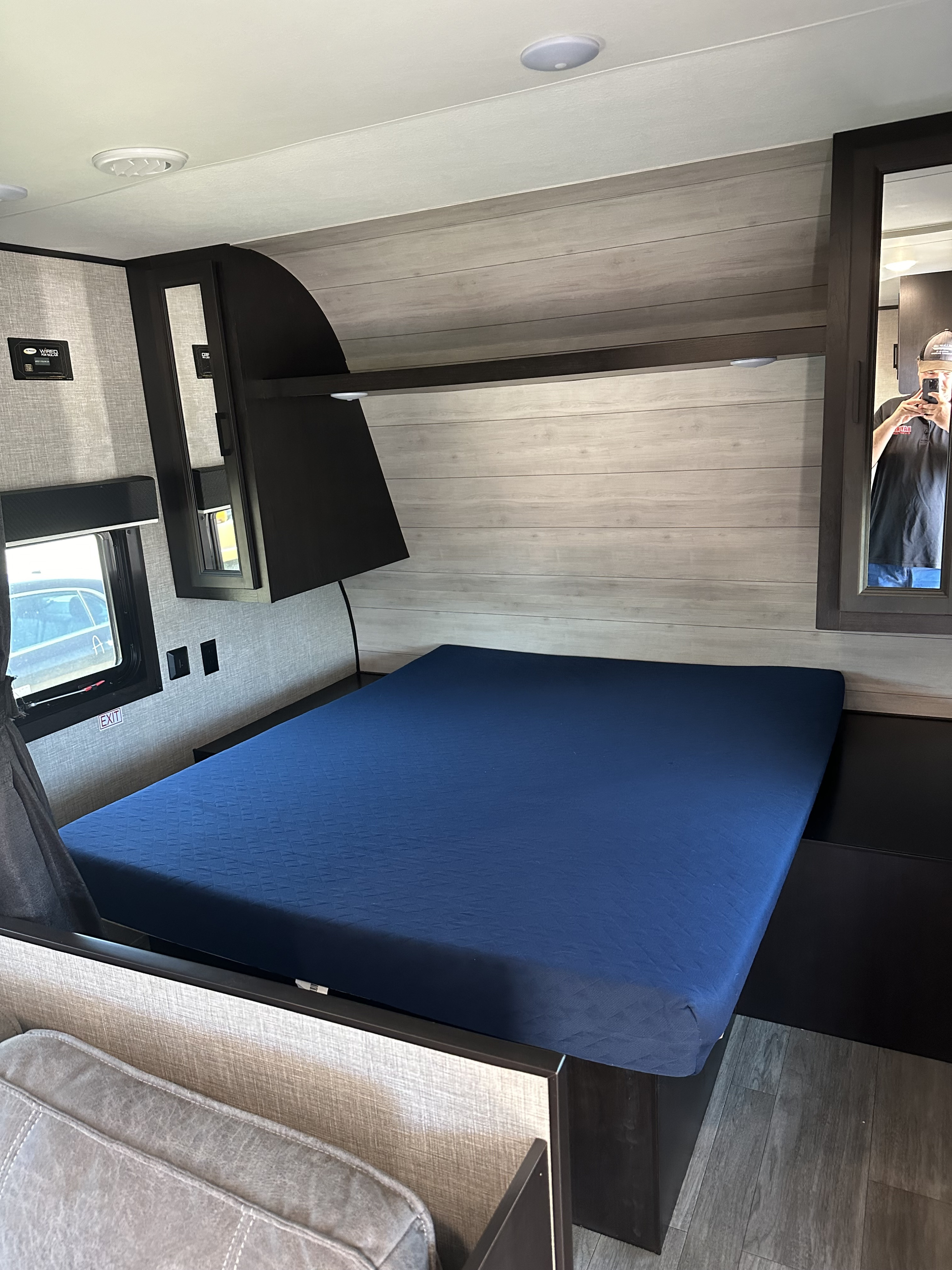 Cozy RV rental bedroom with blue bed, light wood paneling, and overhead storage for a comfortable stay.. Jayco Jay Flight 2022