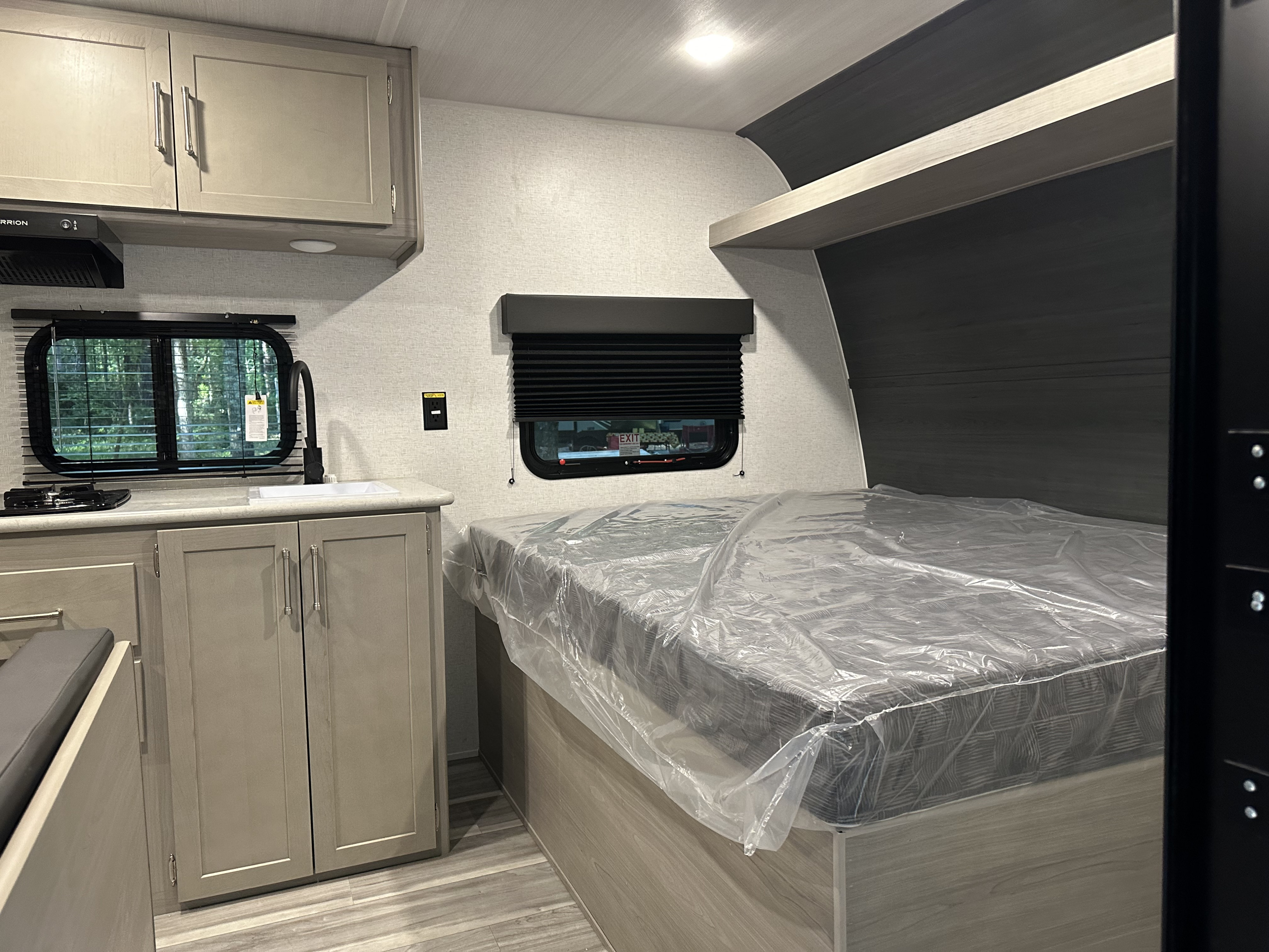Explore this modern RV rental interior! Features a compact kitchen with a sink, stove, light cabinets, and a comfortable bed. Ideal for travel.. Keystone RV Springdale 2024