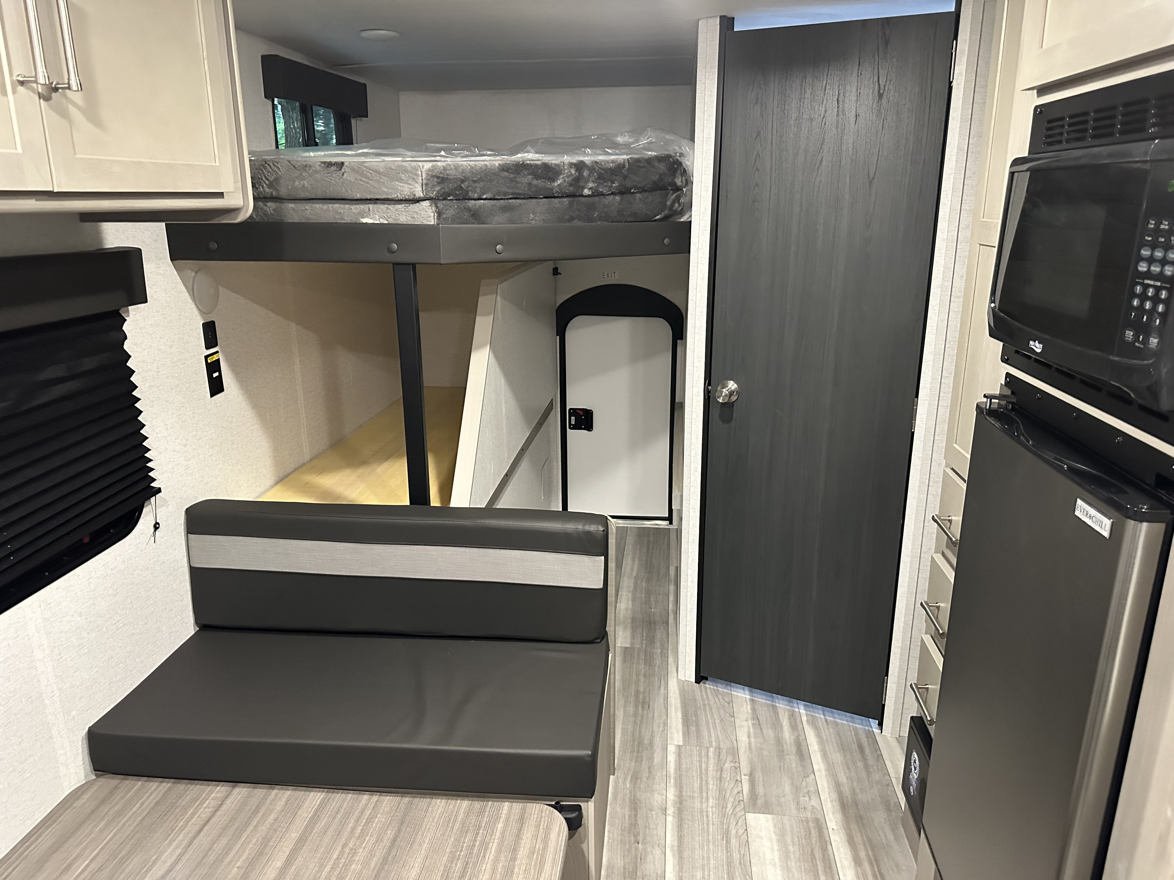 Explore this cozy RV rental interior with bunk bed, dinette, and compact kitchen featuring a microwave & fridge.. Keystone RV Springdale 2024