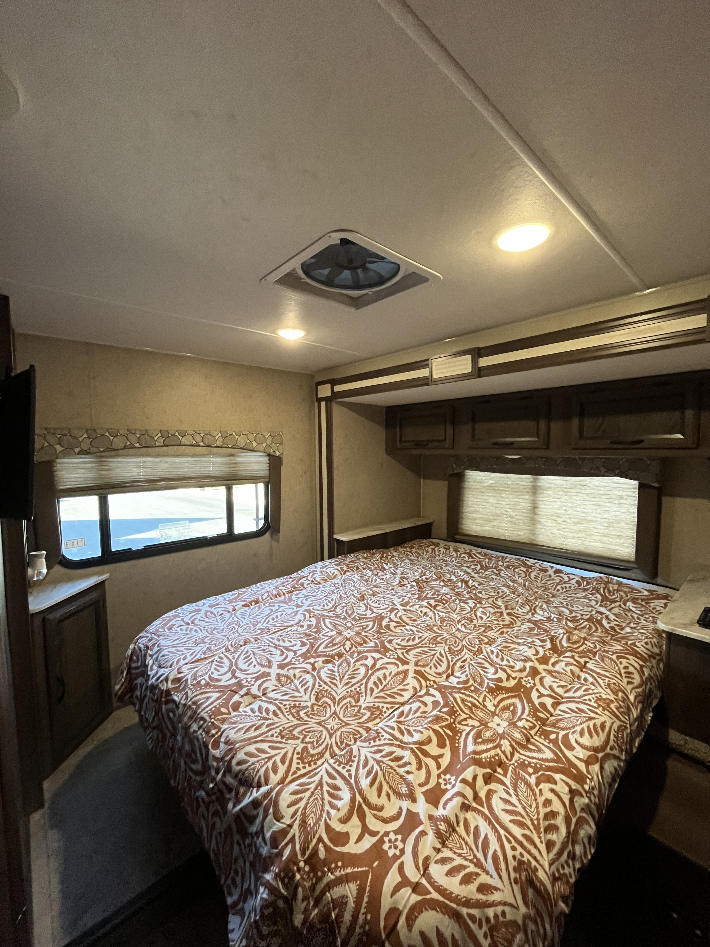 Comfortable RV rental bedroom featuring a decorative comforter, window views, and ample storage for your journey.. Coachmen Freelander 2019