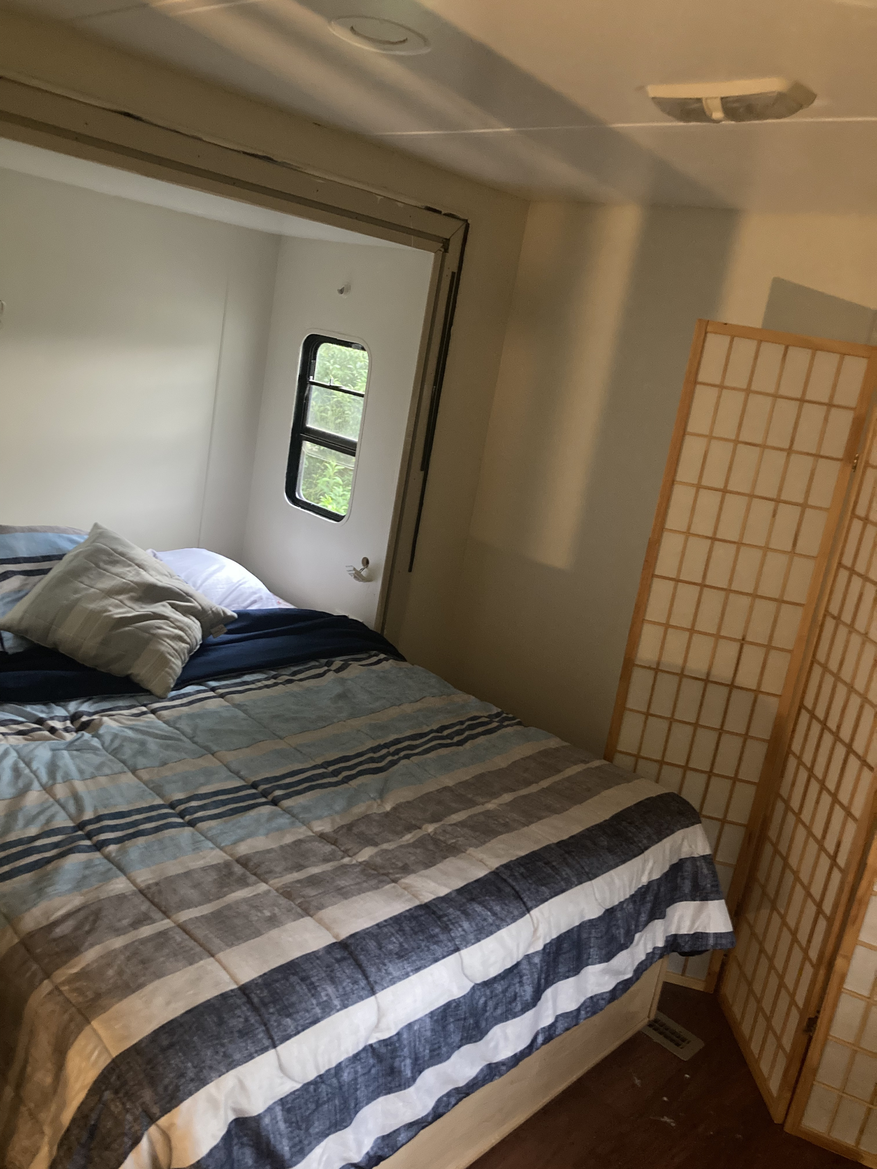 Experience our RV rental's comfortable bedroom with a striped comforter, small window, and a Japanese-style divider.. Monaco Monarch SE 2006