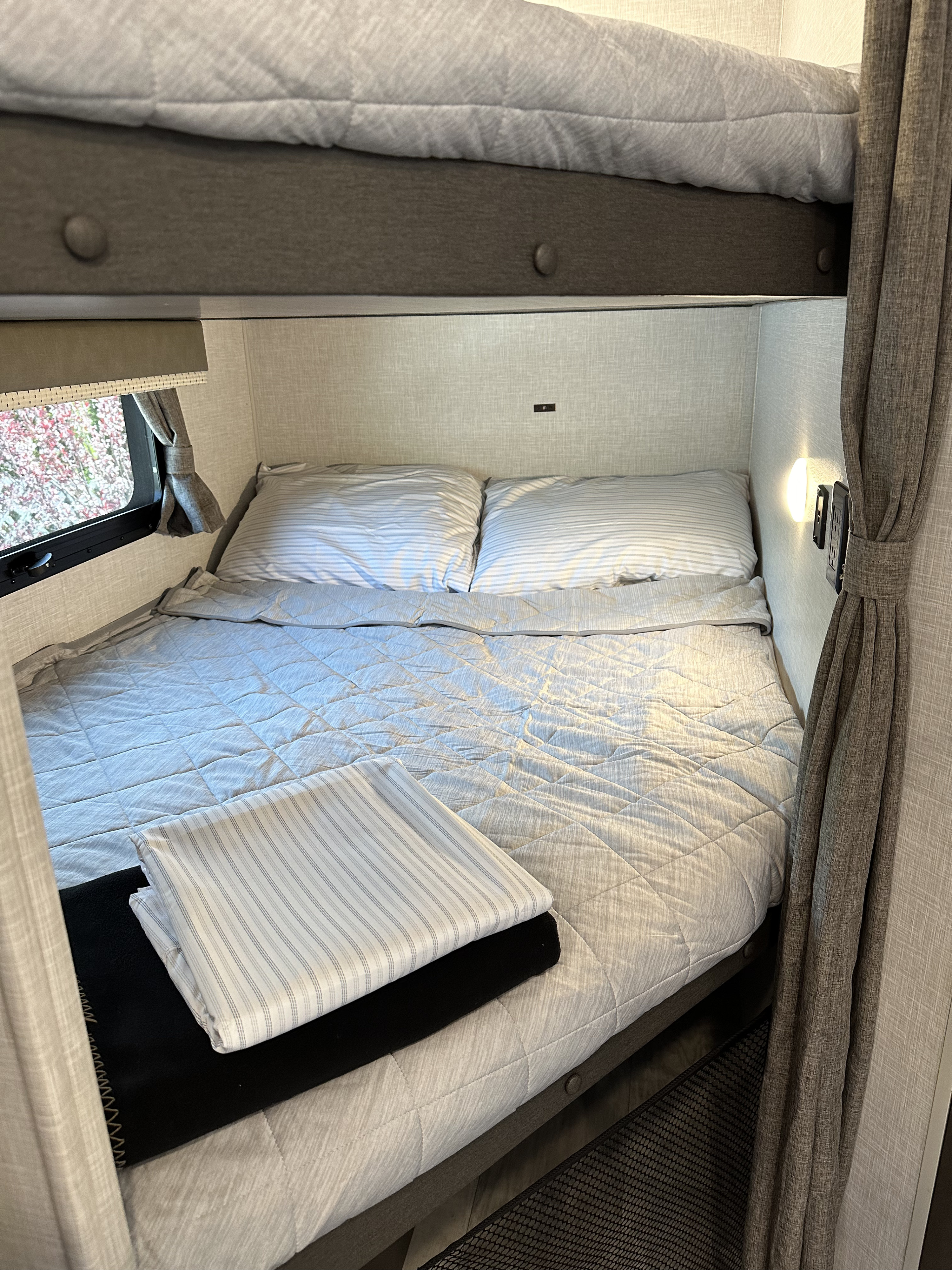 RV rental interior: A compact bedroom with comfortable bunk beds, a window, and bedside amenities.. Forest River Rockwood Mini Lite 2022