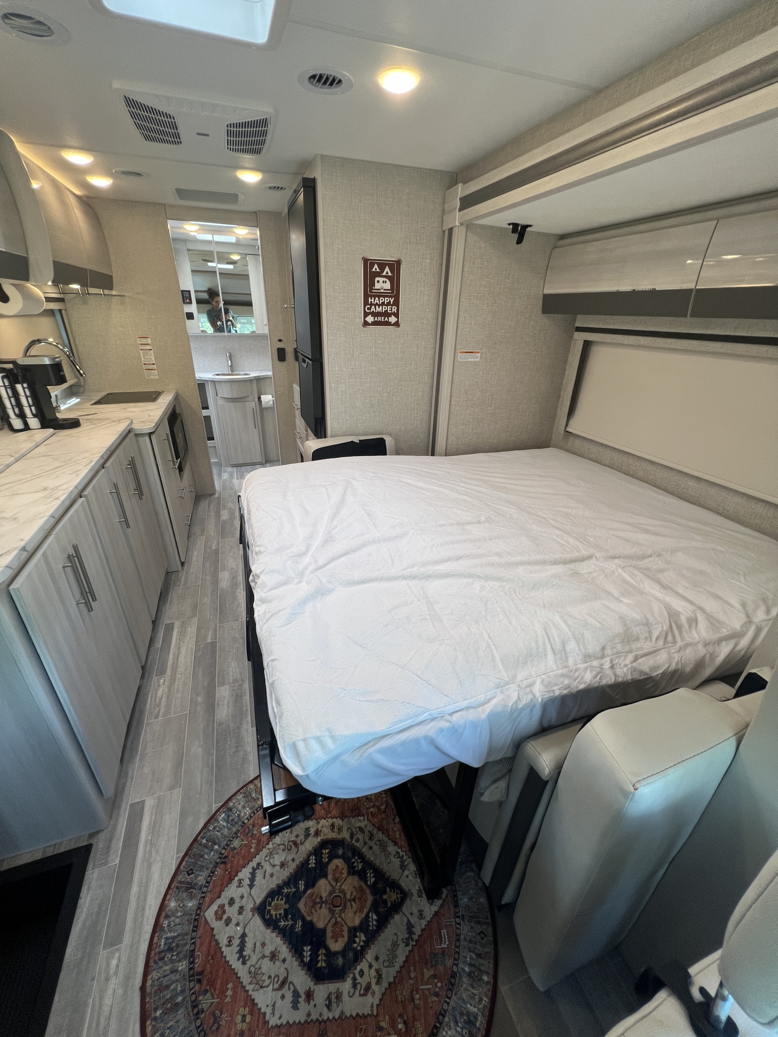 View the inviting interior of an RV rental: a modern compact kitchen, comfortable bed, and accessible bathroom.. Thor Compass 2024