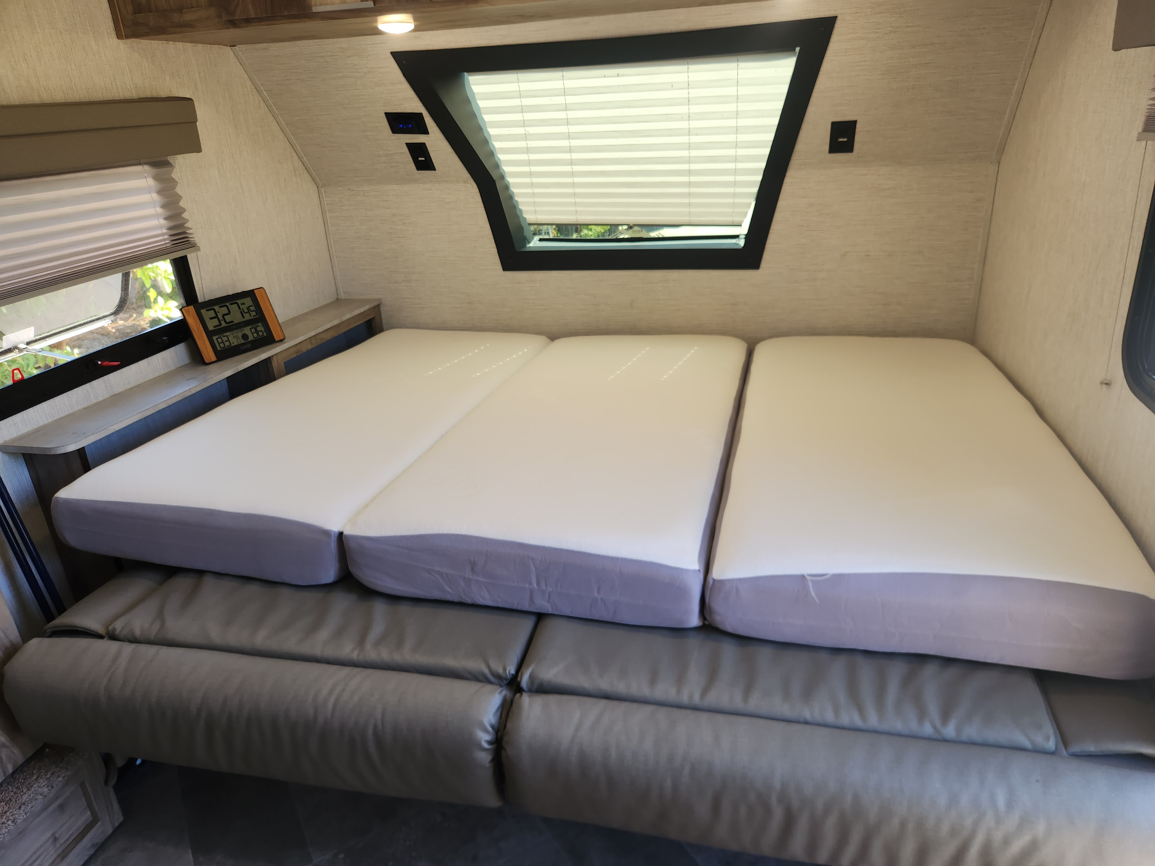 Comfortable RV rental interior with convertible bed and seating area, featuring windows and a digital clock.. Palomino Real Lite Mini 2022