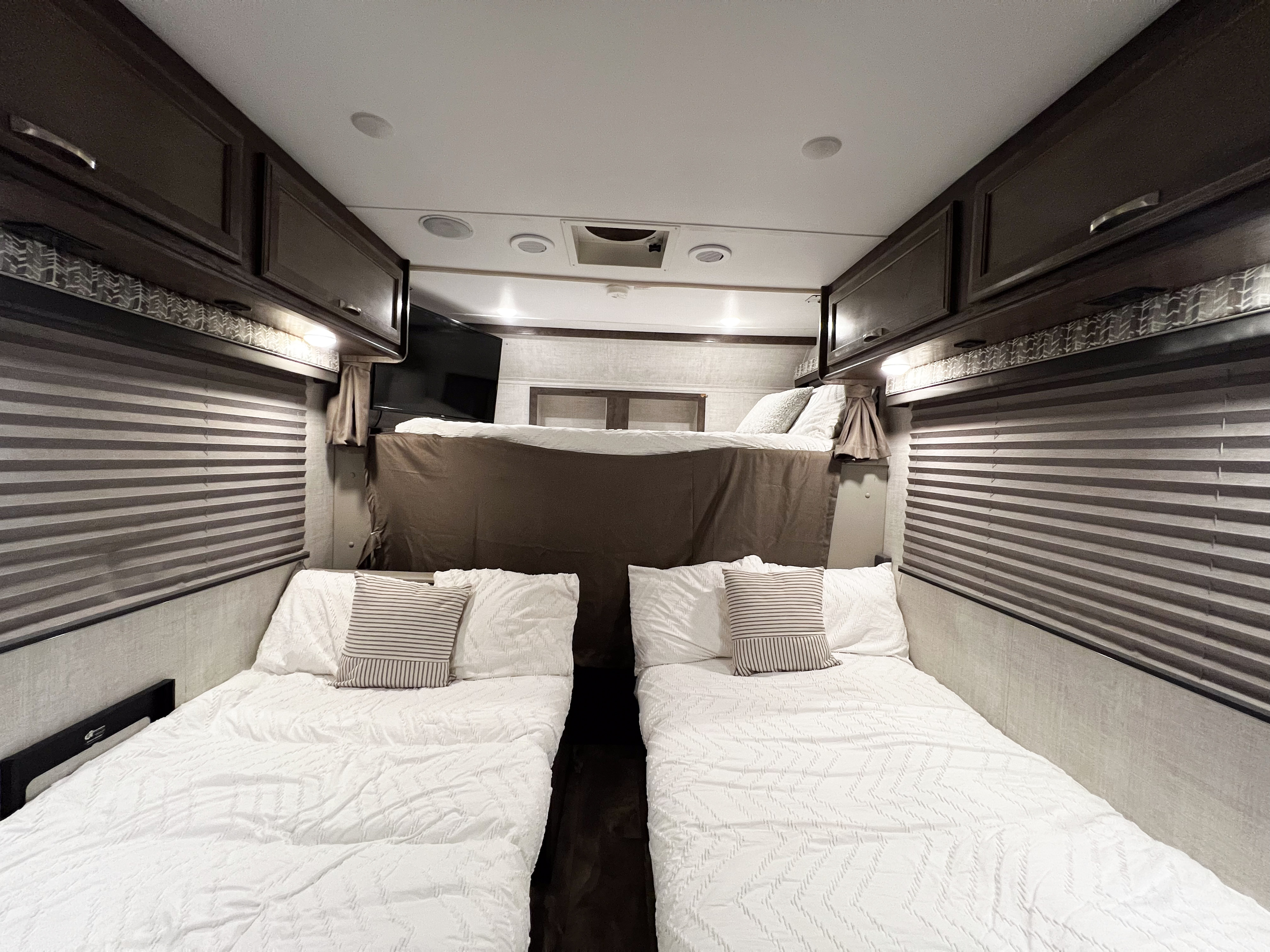 RV rental interior with two lower beds & an upper bunk, offering comfortable family sleeping arrangements.. Gulf Stream Conquest 2022