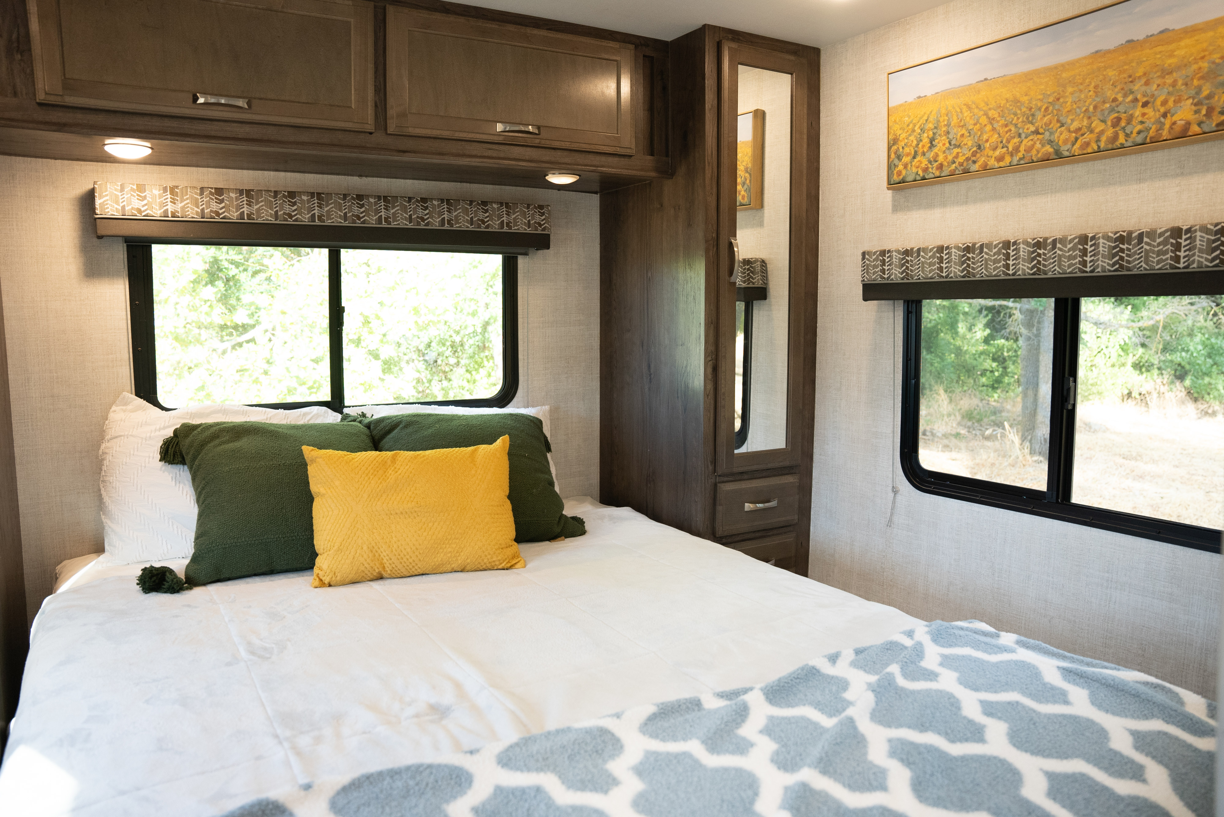 Spacious RV rental bedroom with a cozy bed, vibrant pillows, windows with outdoor views, and built-in storage.. Gulf Stream Conquest 2022