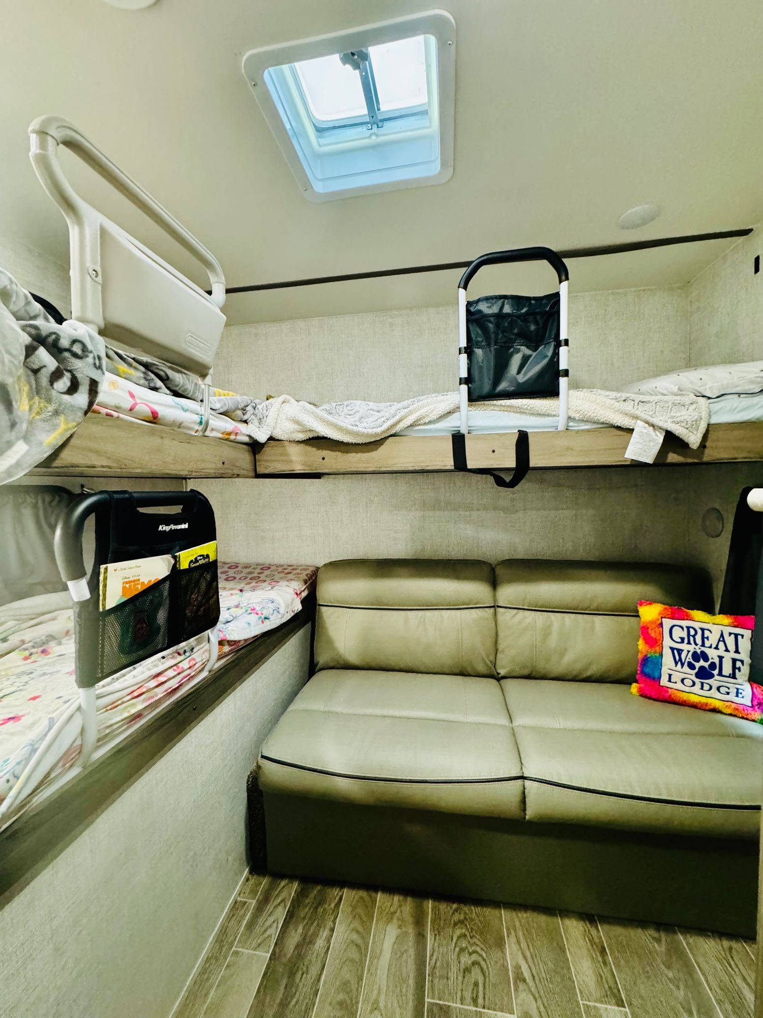 RV rental interior features stacked bunk beds, safety rails, a skylight, and a light-colored sofa.. Gulf Stream Ameri-Lite 2021