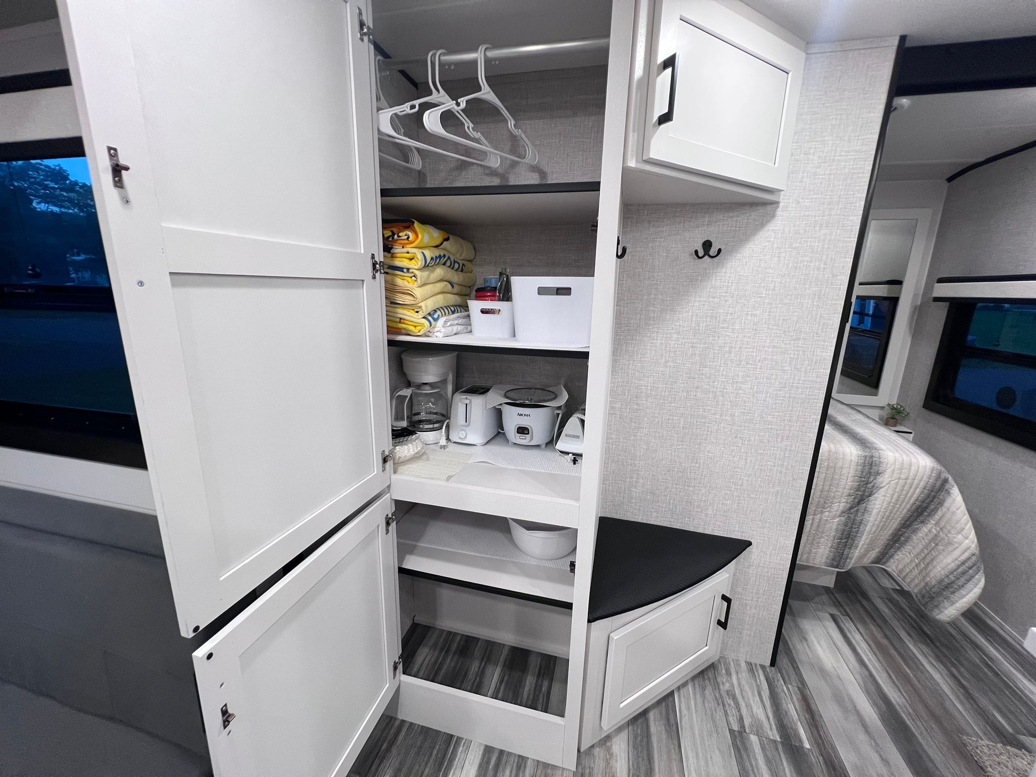 RV rental: Organized interior featuring a closet with hangers, folded towels, small appliances, and a nearby bed.. Jayco Jay Feather 2024
