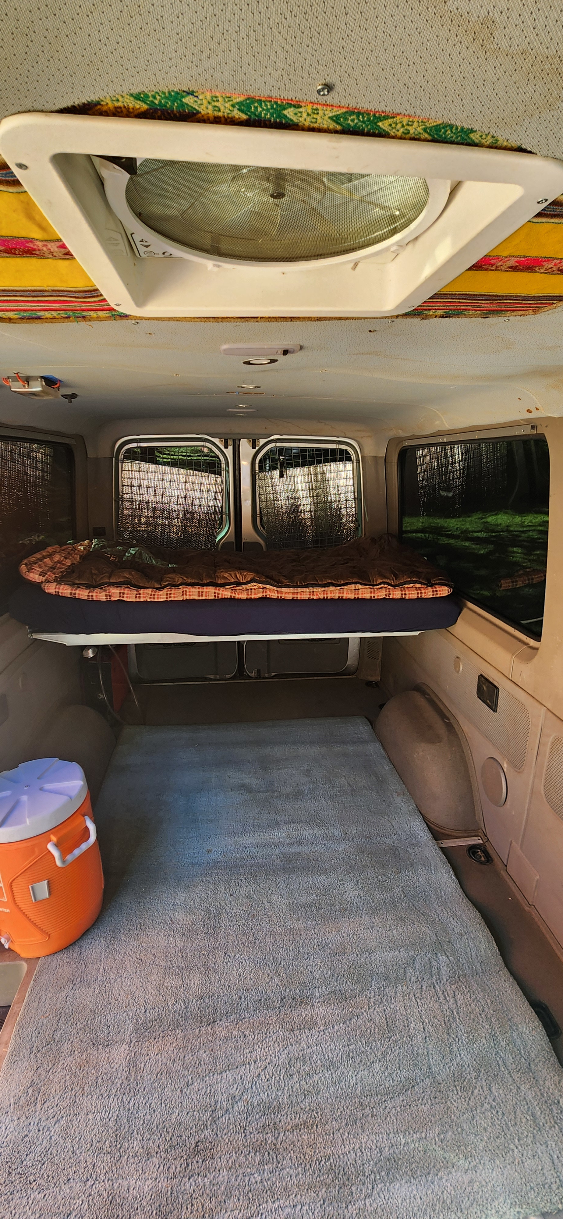 Inside an RV rental: a cozy elevated bed, ample floor space with a rug, and a ceiling fan for comfort.. Dodge Sprinter Van 2007